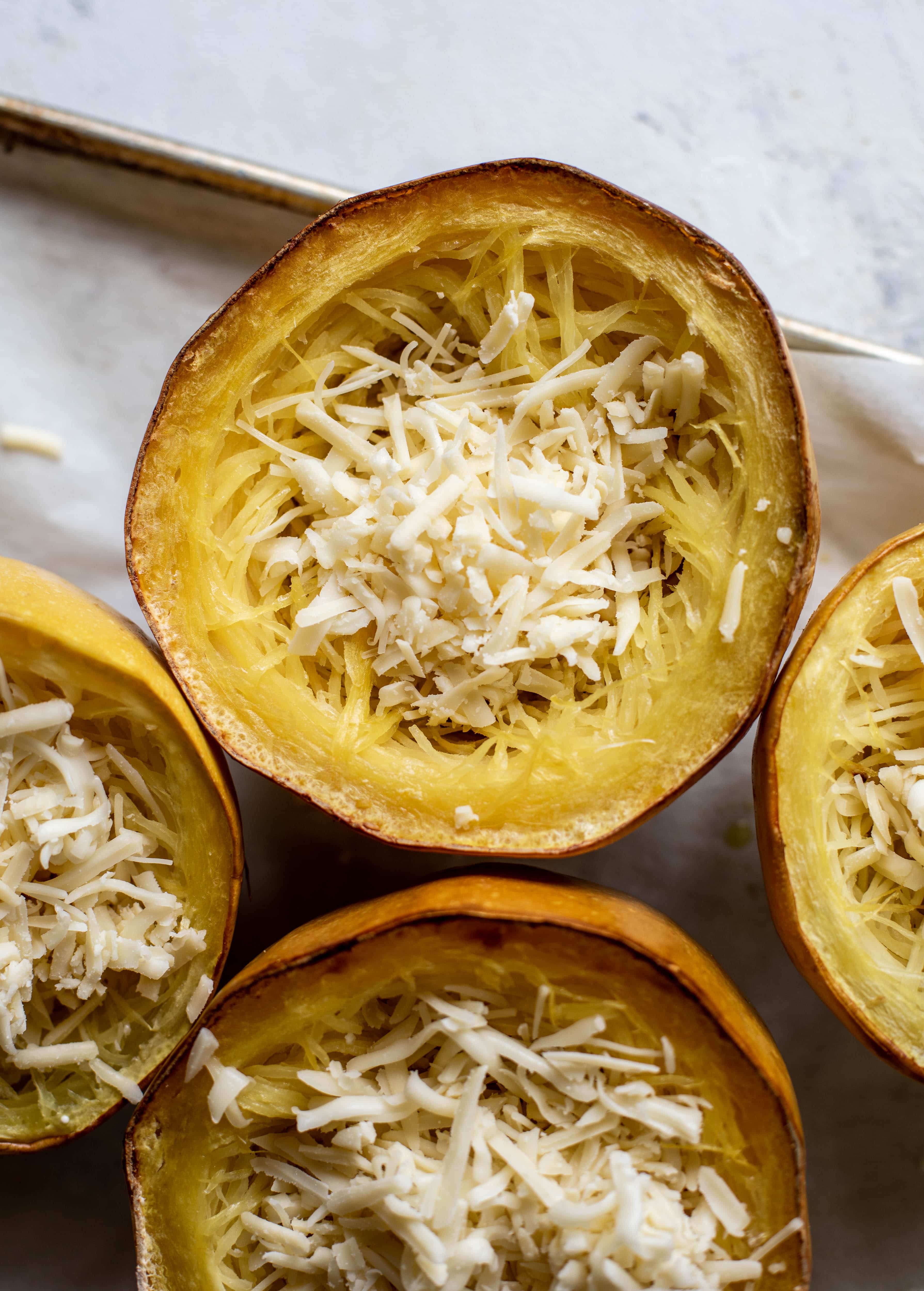 Three cheese spaghetti squash in a squash bowl! Squash tossed with fontina, gruyere and parmesan to make a creamy comforting meal.