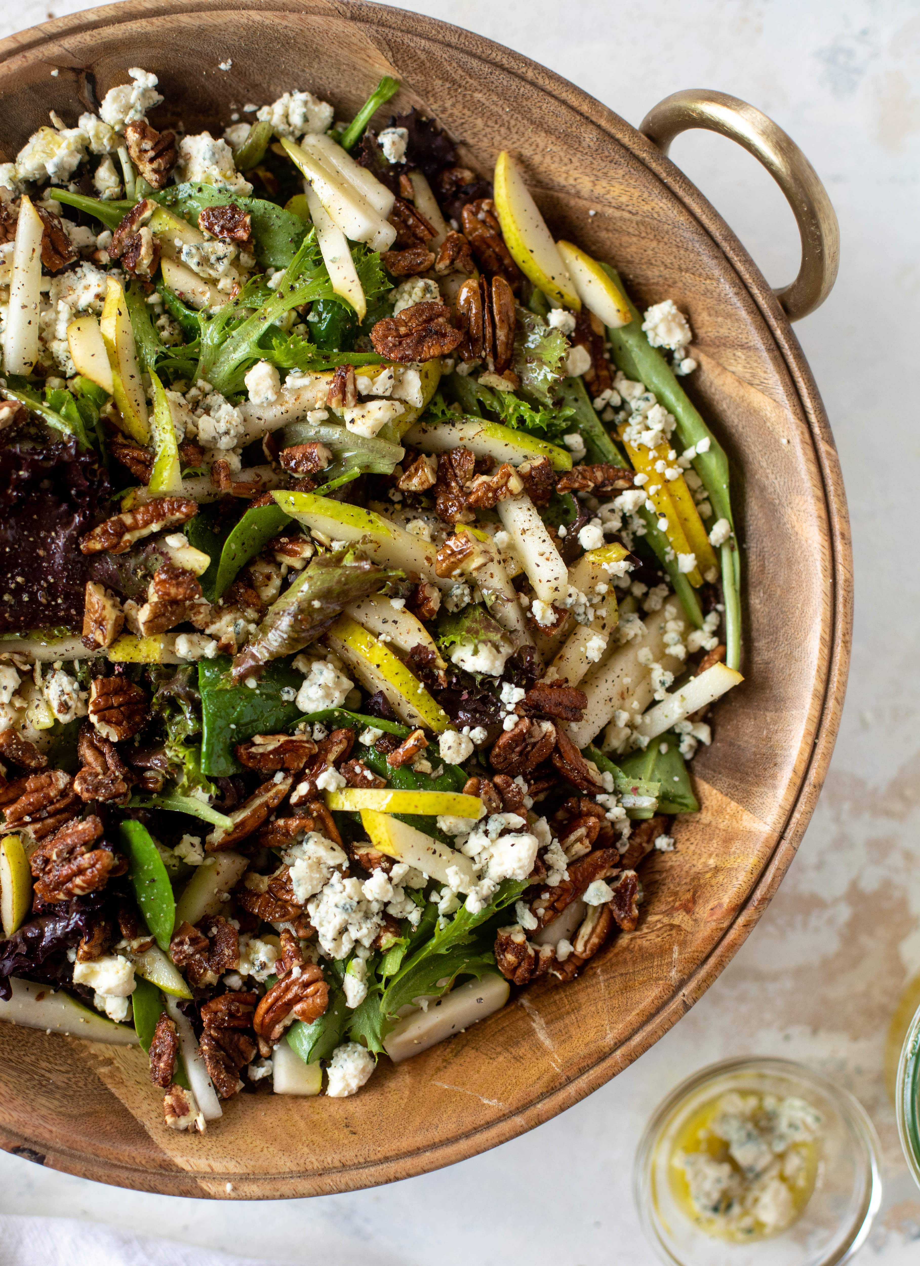 This pear gorgonzola is the perfect simple greens salad for the holiday and winter season! Topped with sweet and spicy pecans and champagne vinaigrette!