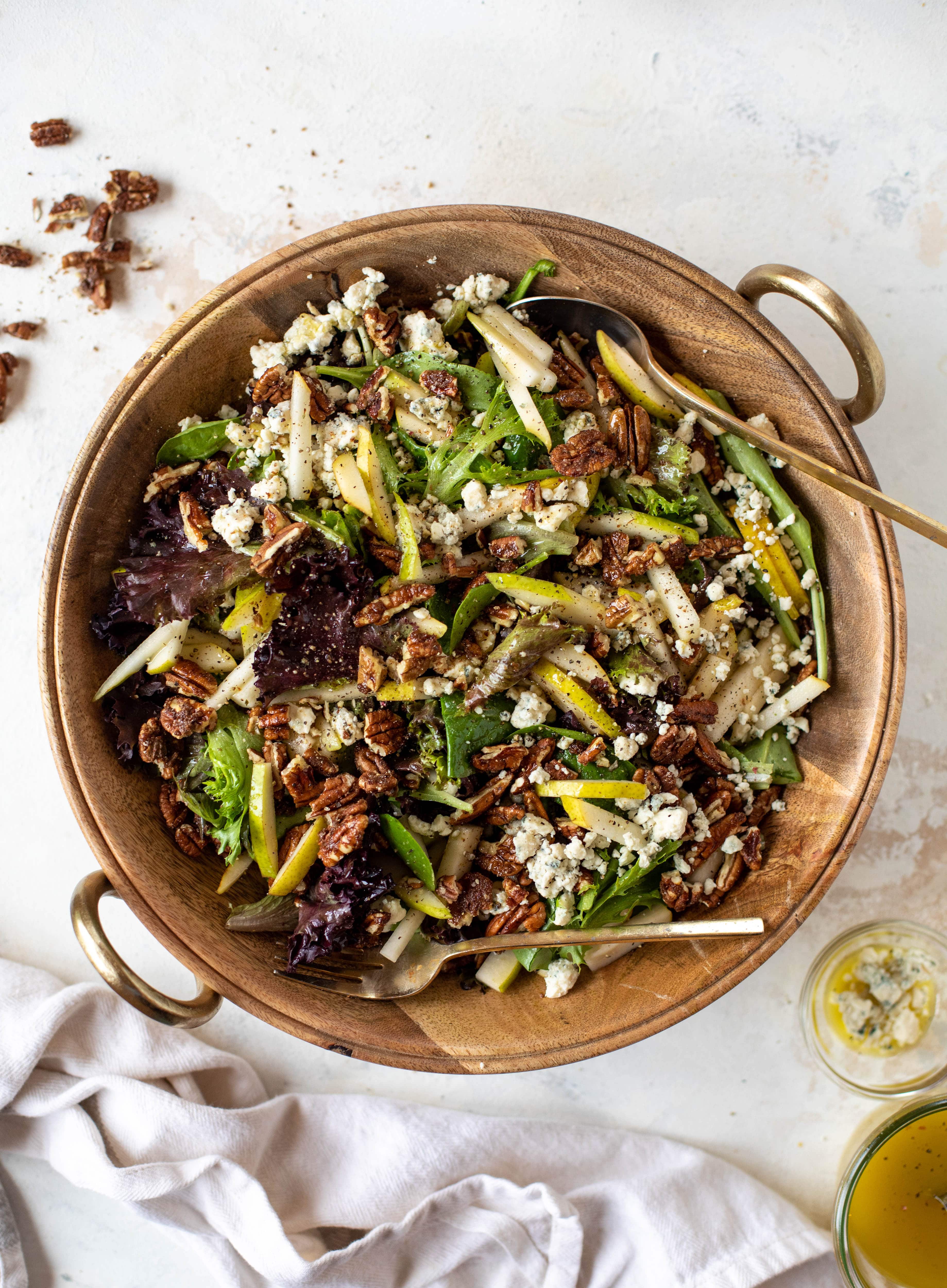 This pear gorgonzola is the perfect simple greens salad for the holiday and winter season! Topped with sweet and spicy pecans and champagne vinaigrette!