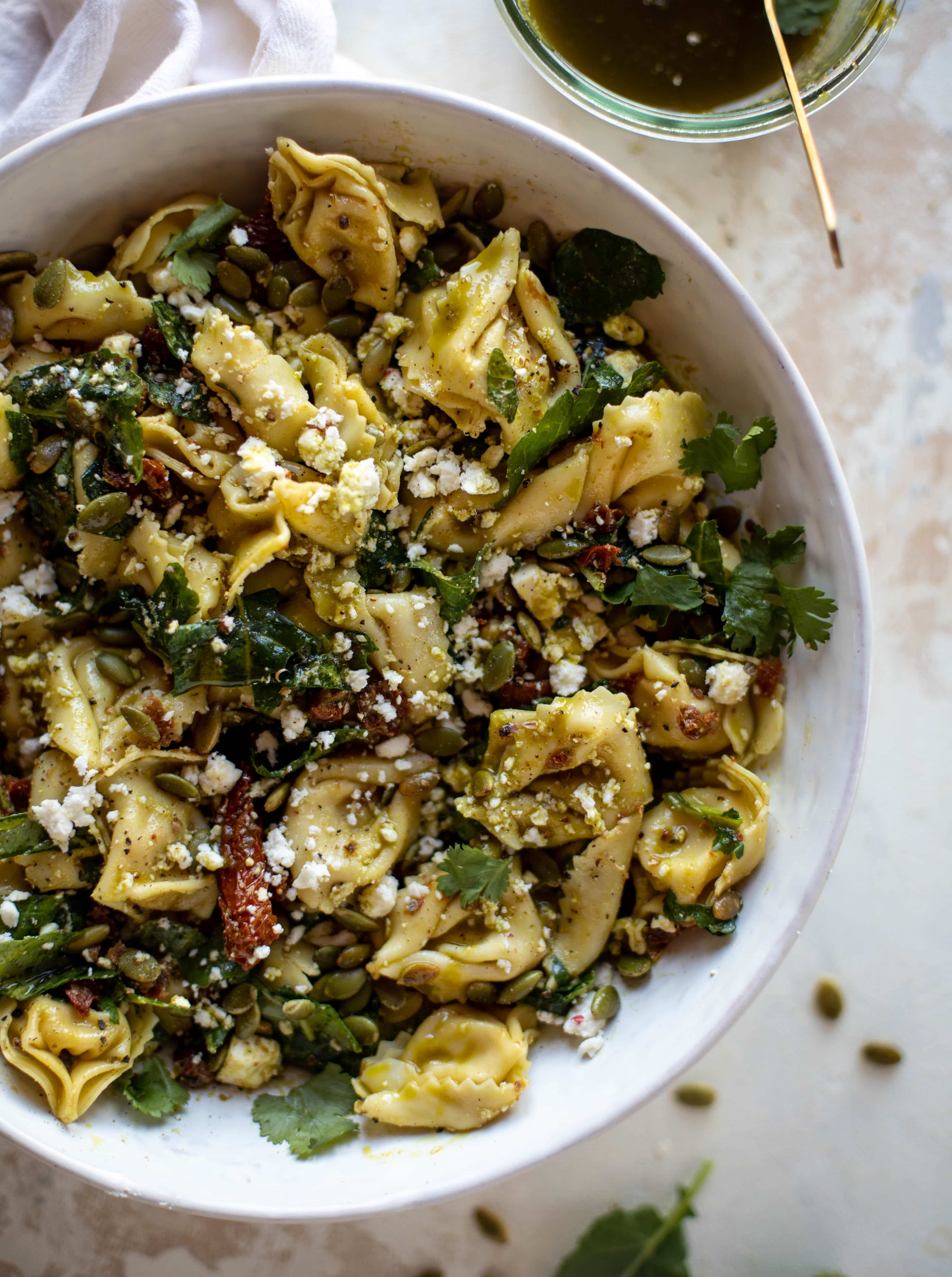This cilantro lime tortellini salad is loaded with flavor! Served warm or cold, it has pepitas, sun dried tomatoes and crumbled feta. It's ridiculously good! 