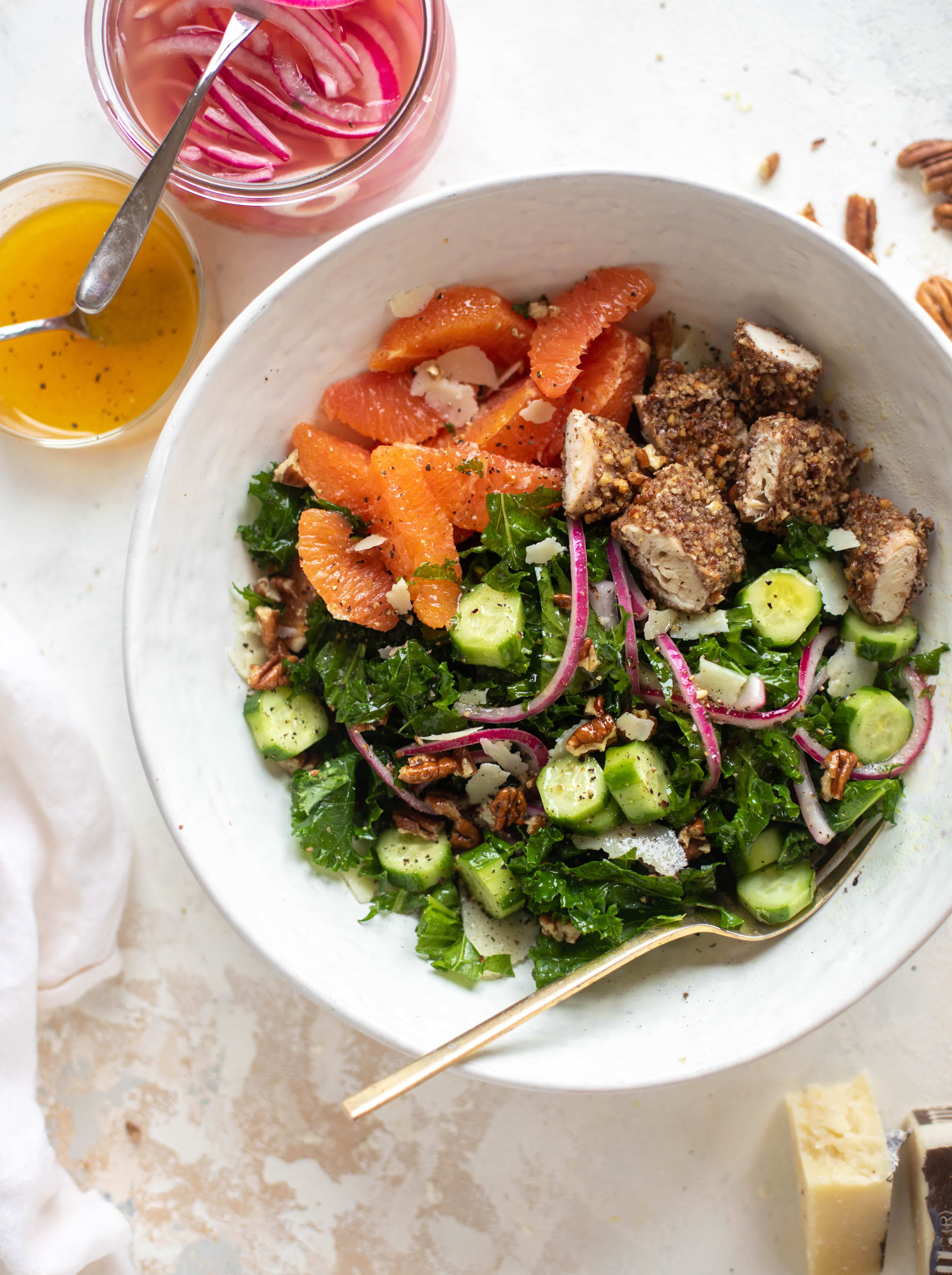 This pecan crusted chicken salad is so hearty! Kale, cara cara oranges, pickled onions, cucumbers and pecorino make this a bowl of flavor.