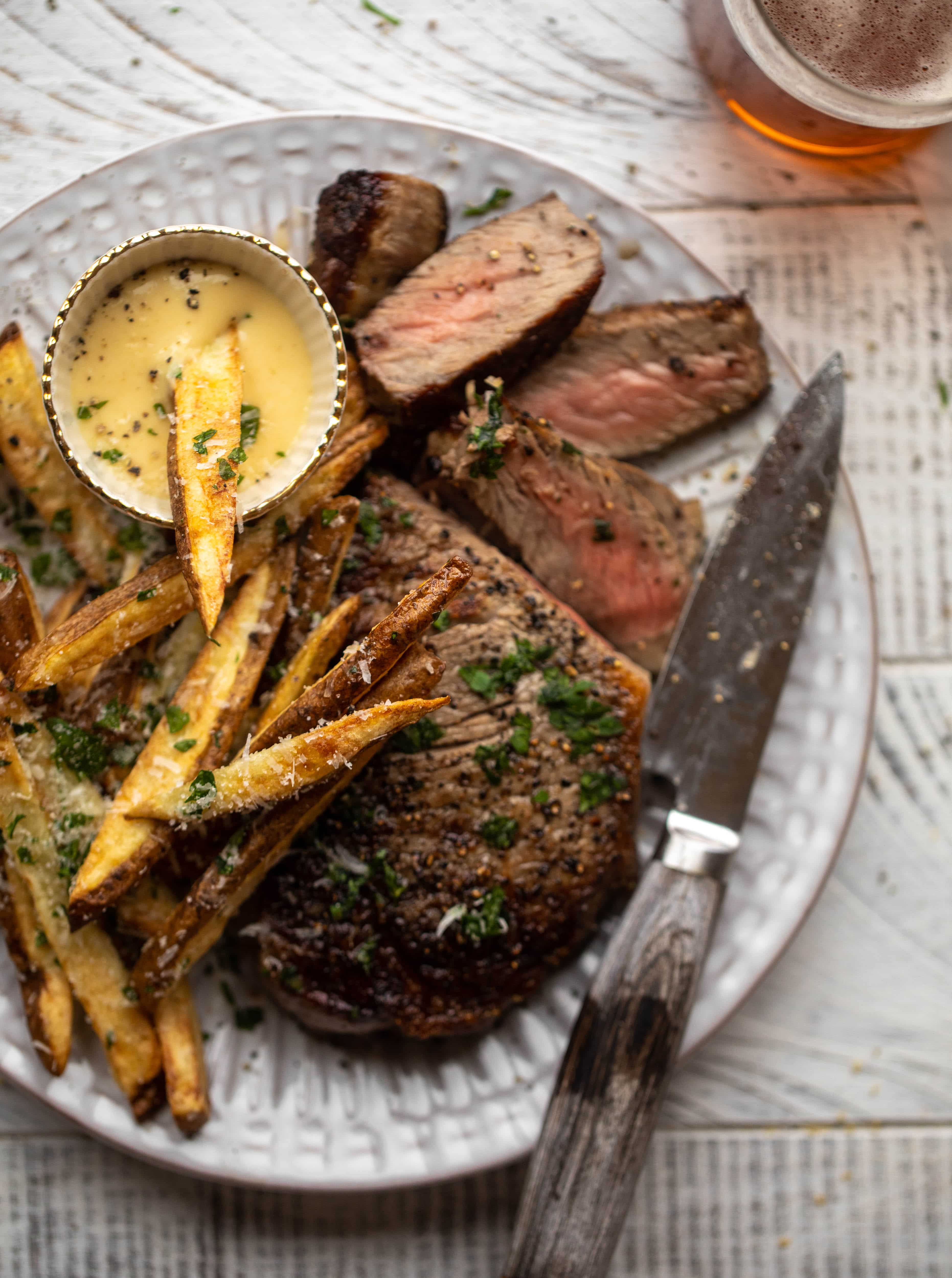 This is our favorite steak frites! Seared skillet steak and crispy fries made in the air fryer, topped with truffle salt, parmesan and herbs!