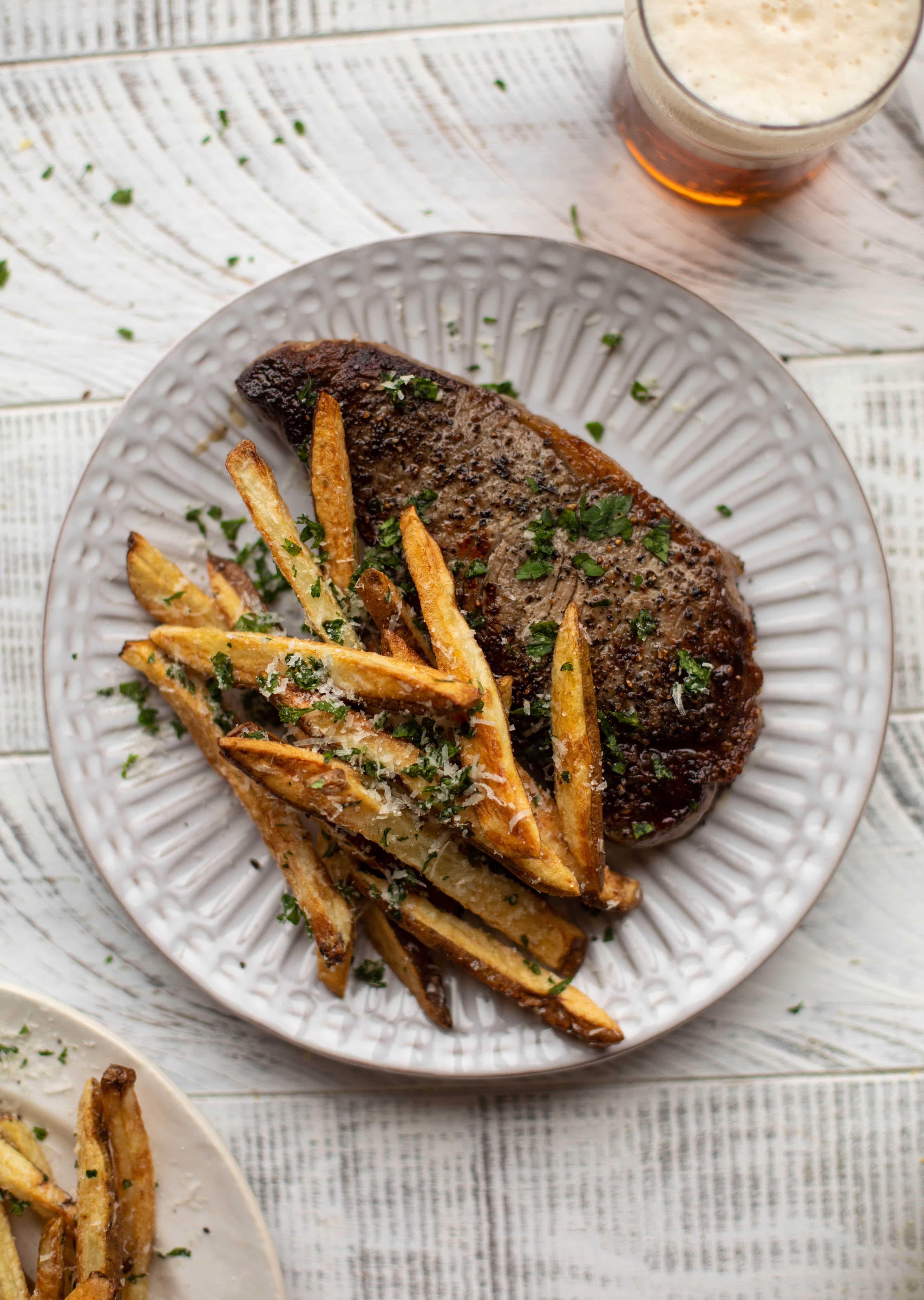 This is our favorite steak frites! Seared skillet steak and crispy fries made in the air fryer, topped with truffle salt, parmesan and herbs!