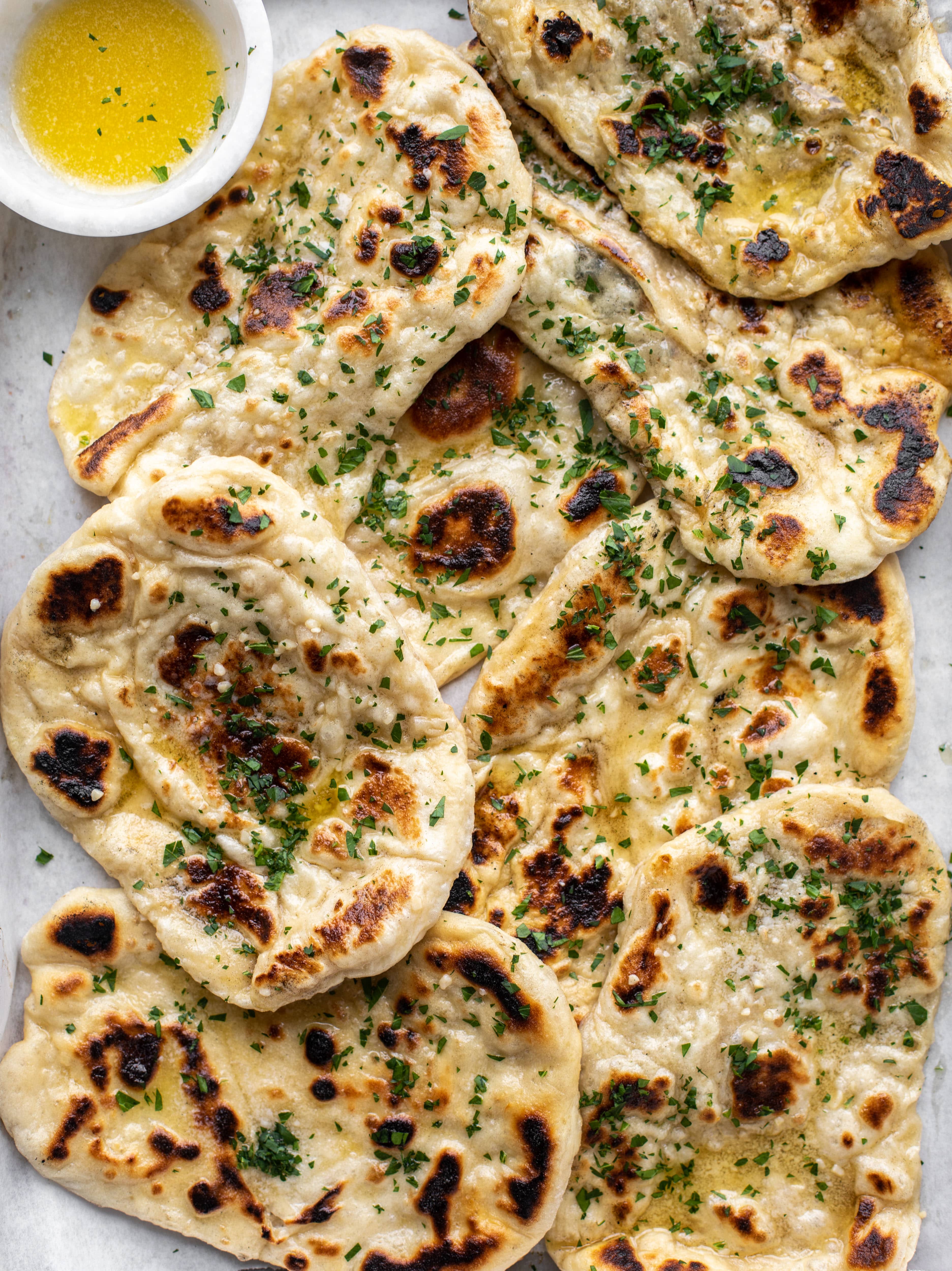 This garlic butter naan bread recipe is divine! It uses baking powder and baking soda instead of yeast and is drenched with garlic butter. So delicious!