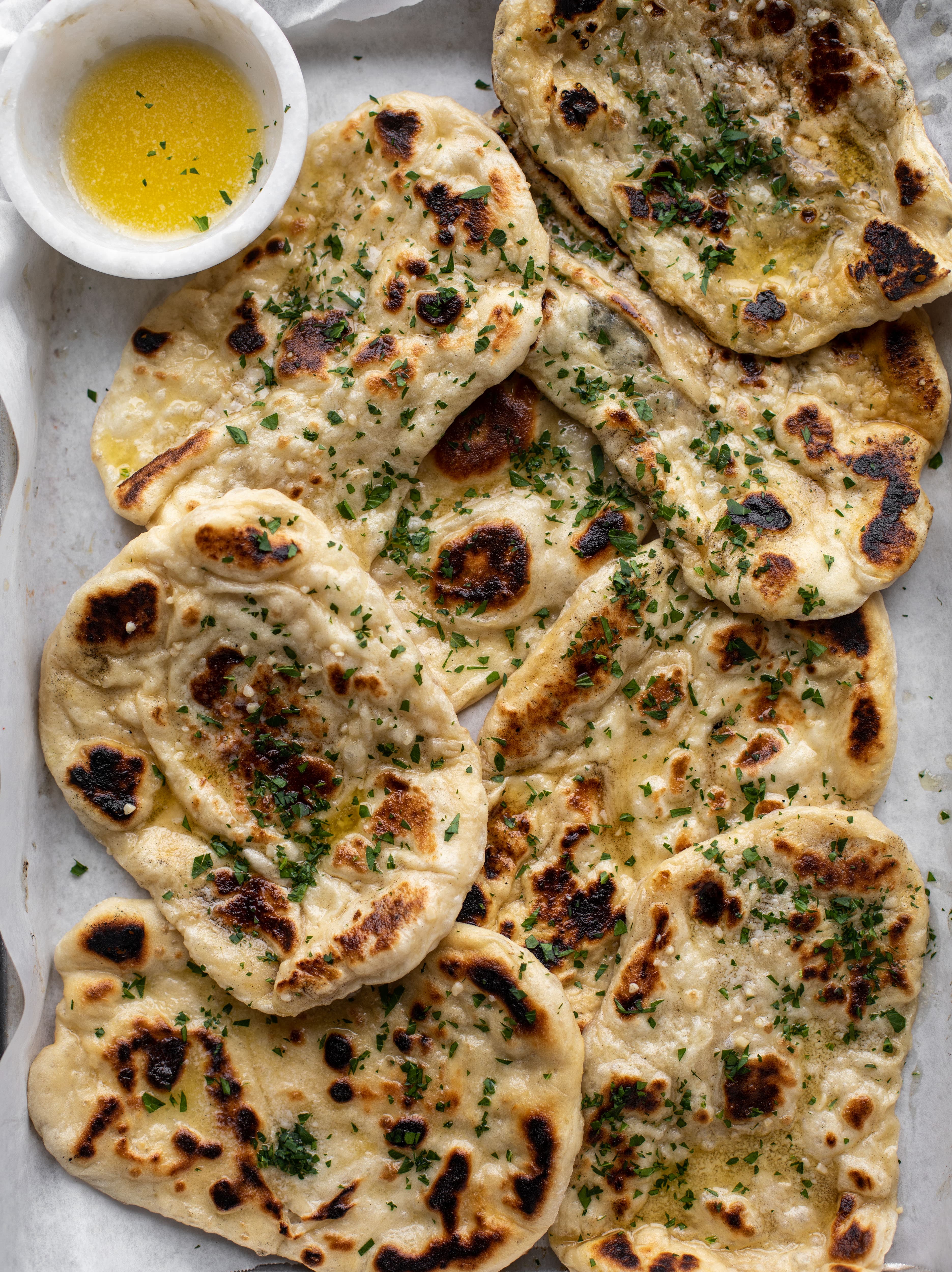 This garlic butter naan bread recipe is divine! It uses baking powder and baking soda instead of yeast and is drenched with garlic butter. So delicious!