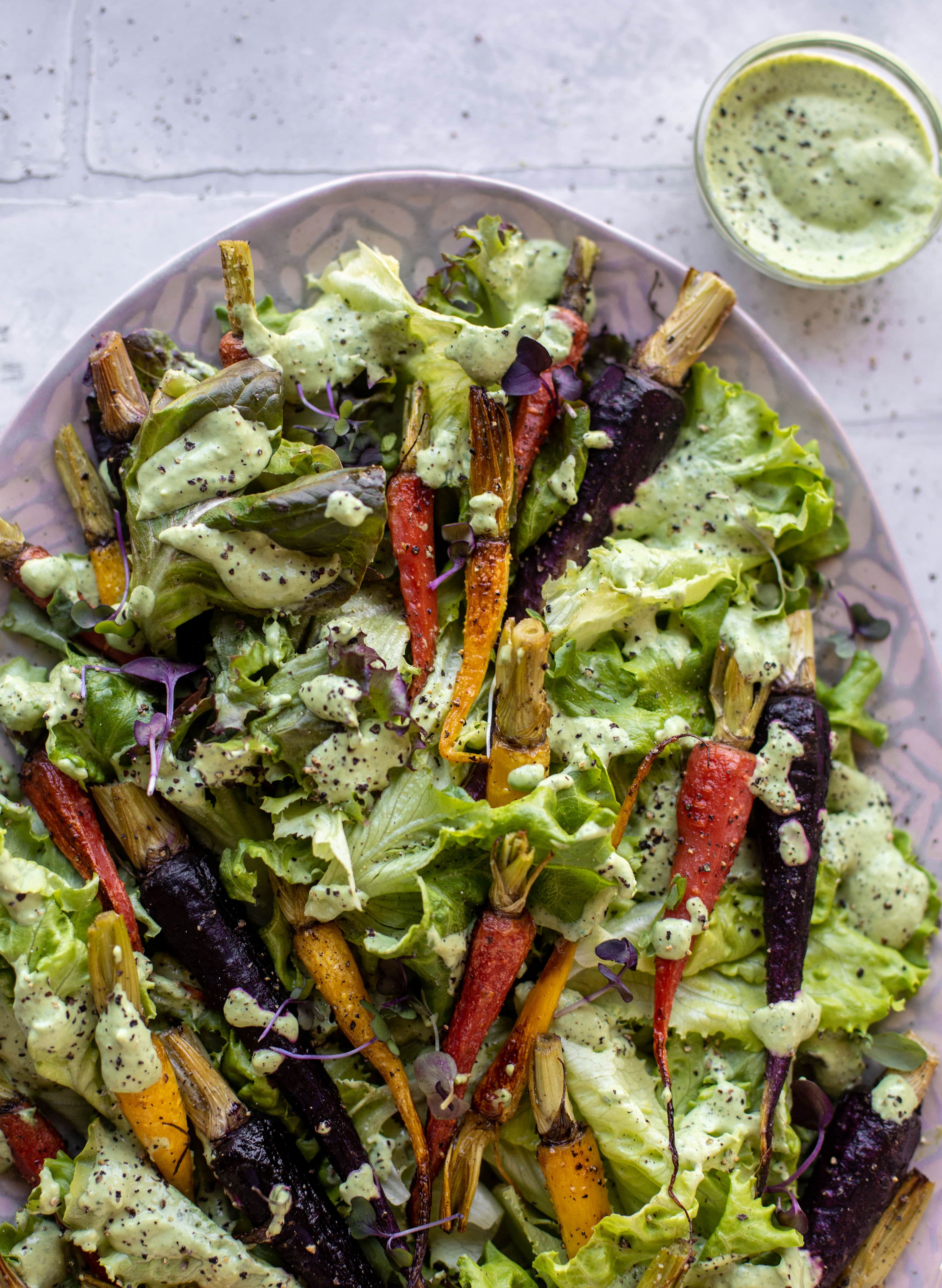 This roasted carrot salad is perfect for spring! Caramely, roasted carrots served over butter greens dressing with green goddess. Simple but delish.