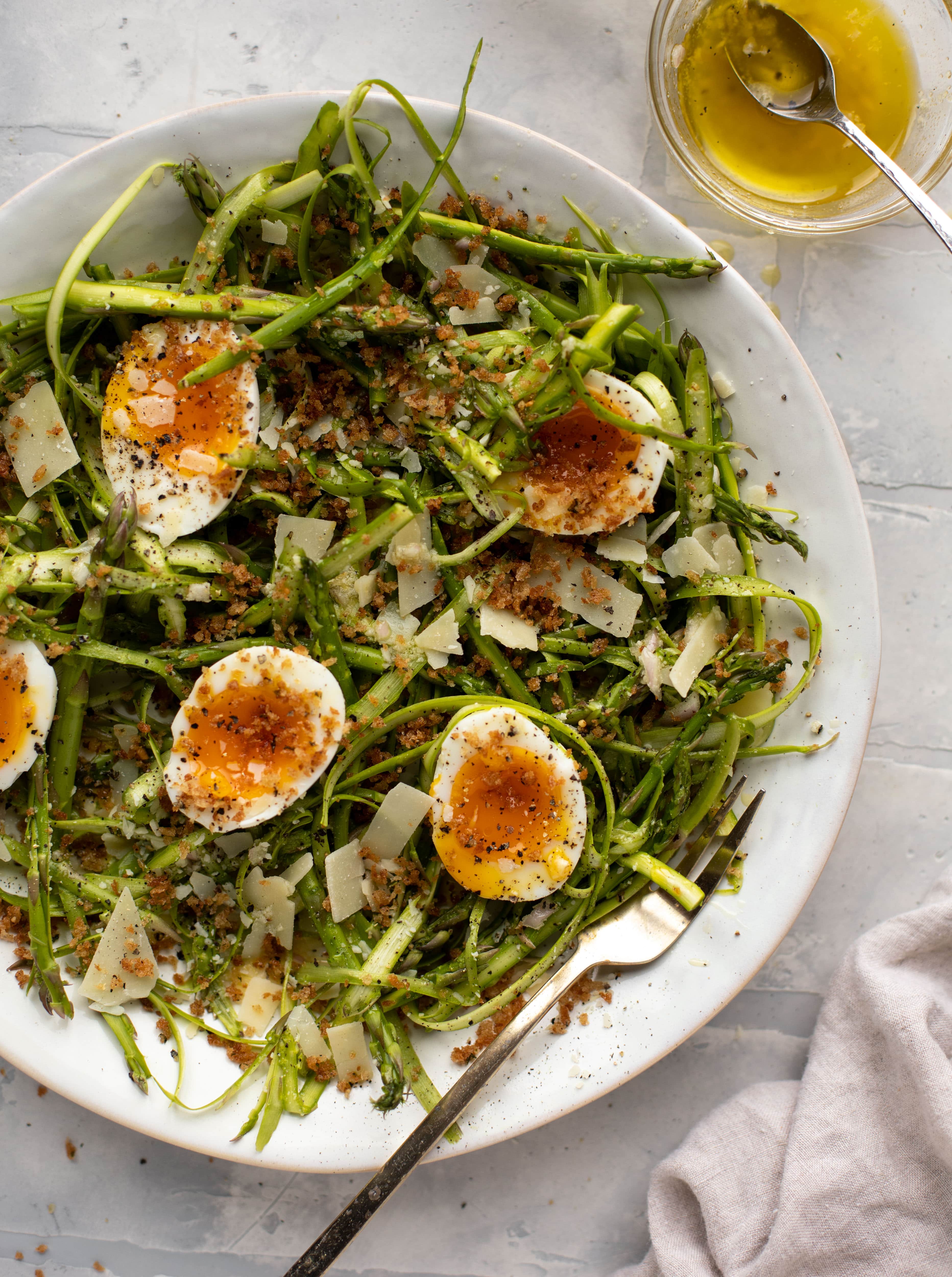 This shaved asparagus salad is tossed with a delicious parmesan vinaigrette, then topped with soft boiled eggs and finished with crunchy garlic breadcrumbs!