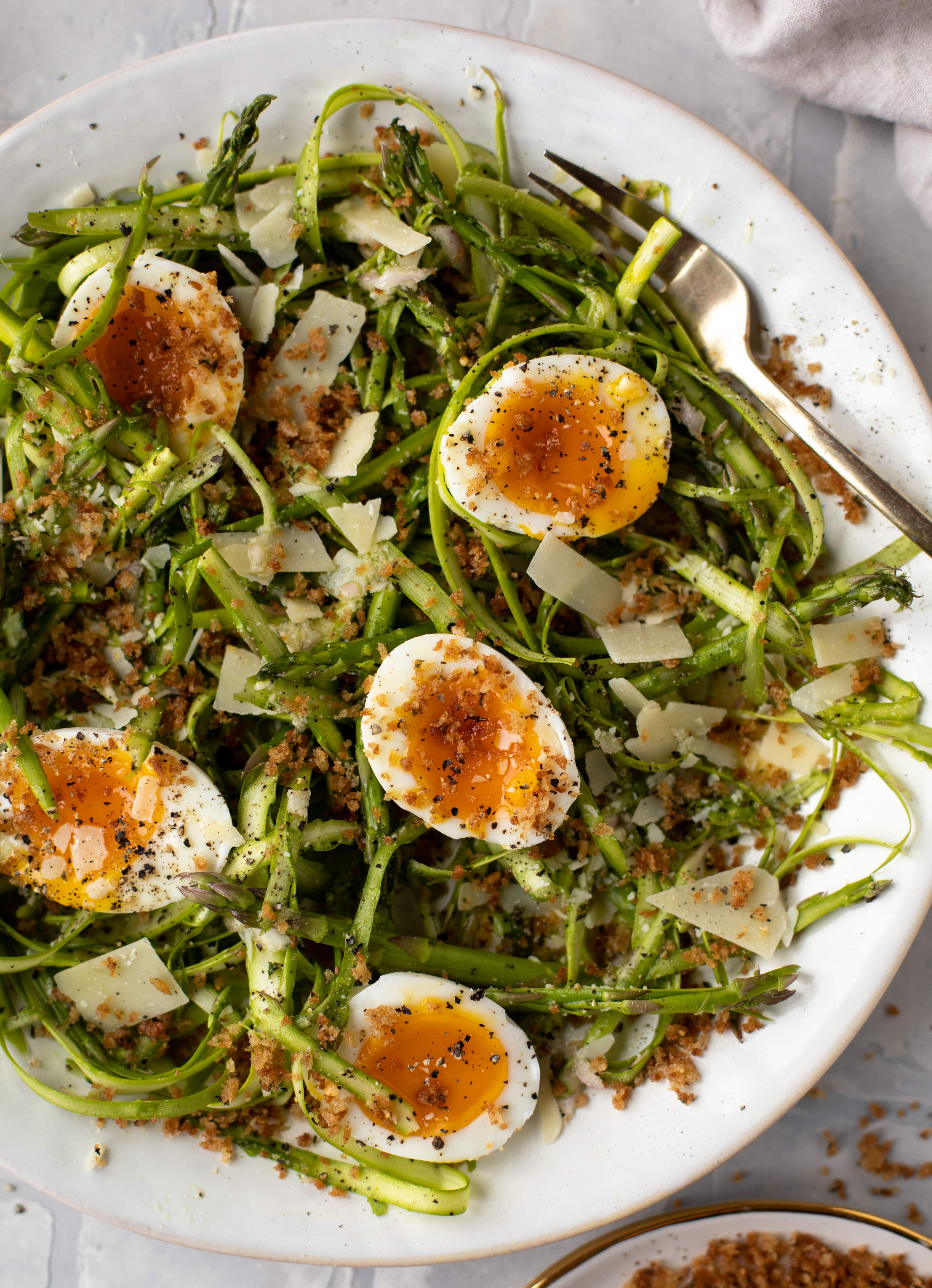 This shaved asparagus salad is tossed with a delicious parmesan vinaigrette, then topped with soft boiled eggs and finished with crunchy garlic breadcrumbs!