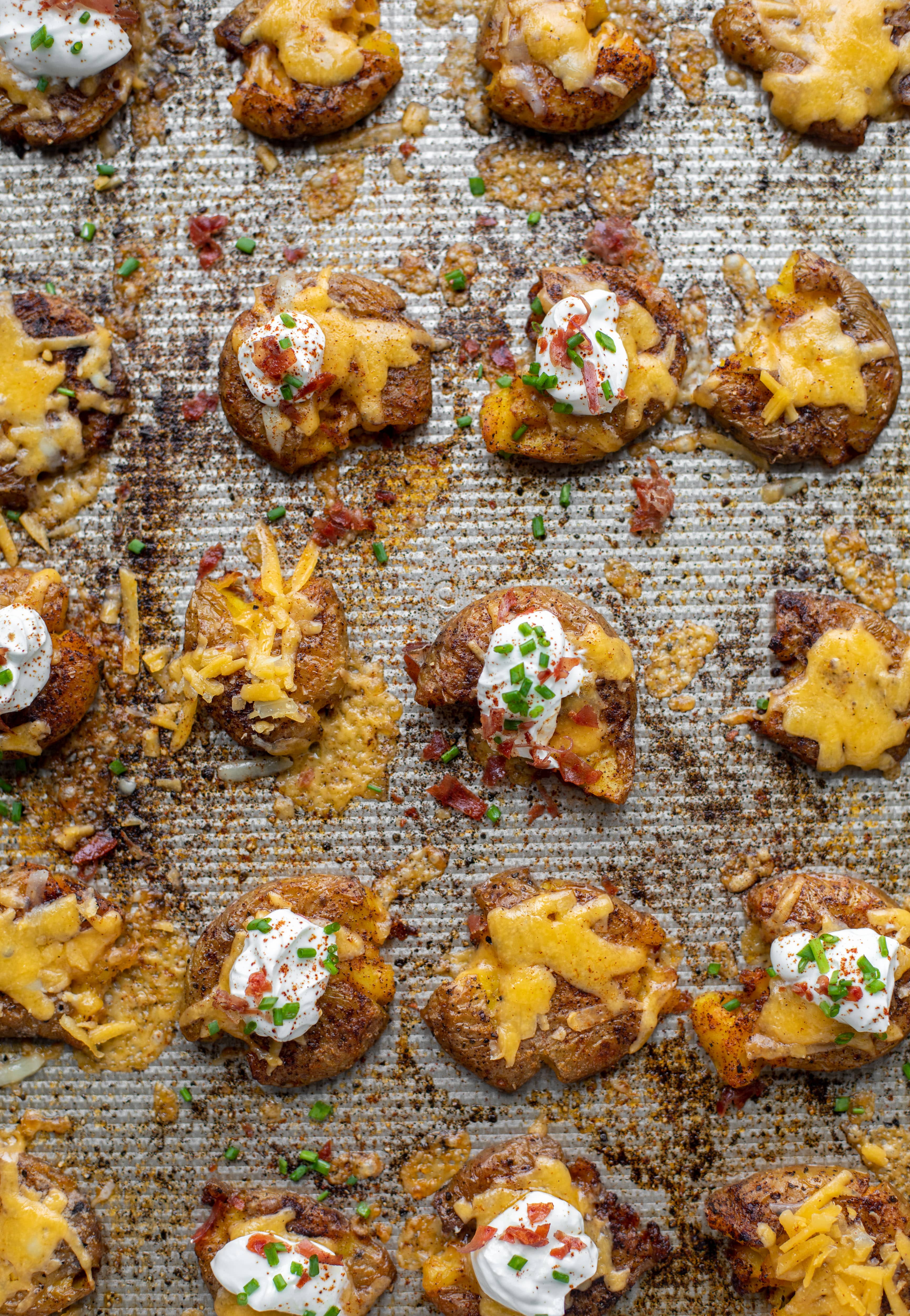 Chipotle cheddar smashed potatoes on a baking sheet. These super crispy chipotle cheddar smashed potatoes are the best side dish. A little spicy and smothered in cheese, they are irresistible. 