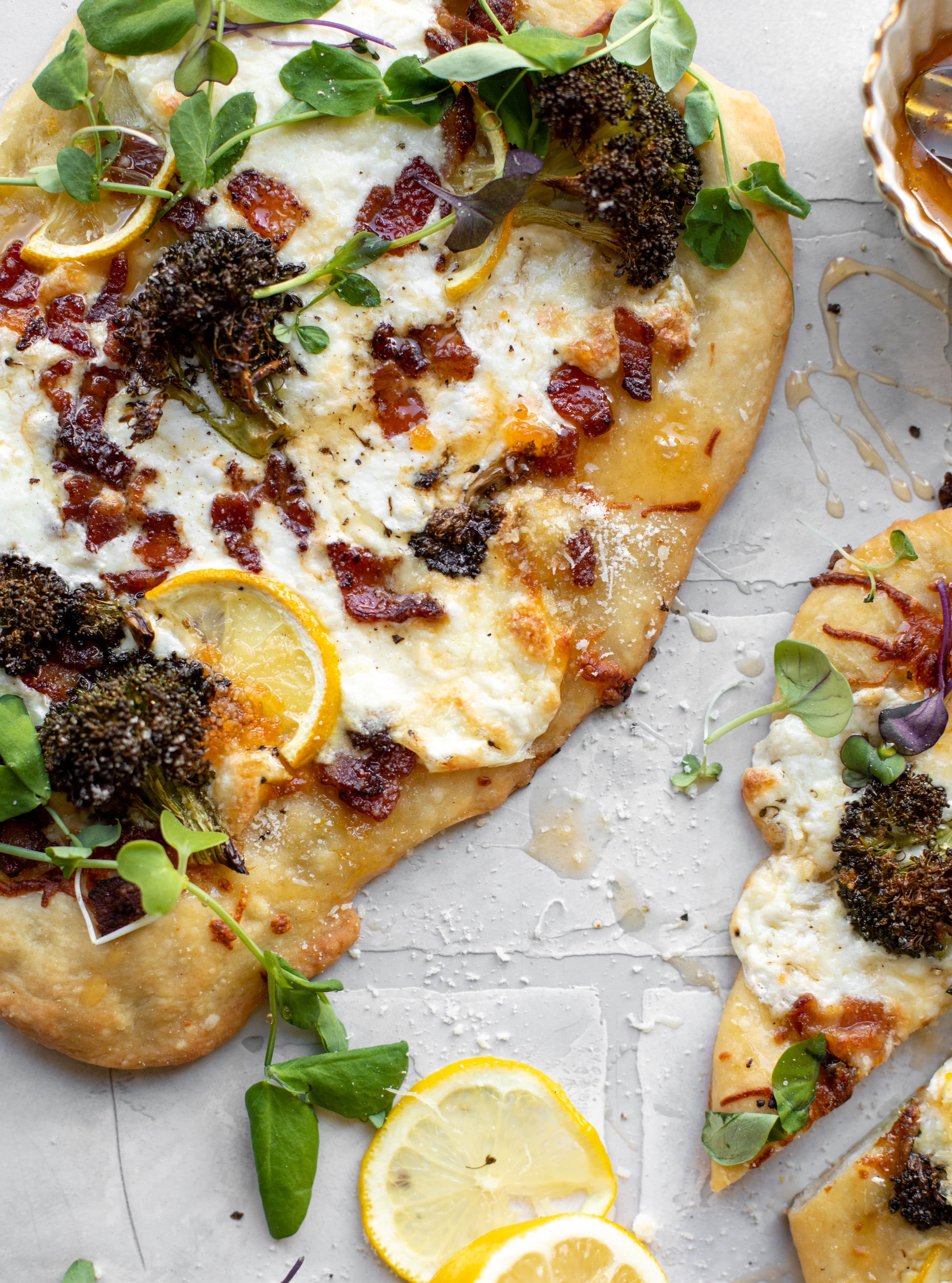 This cheesy lemon flatbread pizza is covered with burrata cheese, parmesan, roasted vegetables and hot honey. It's a flavor dream!