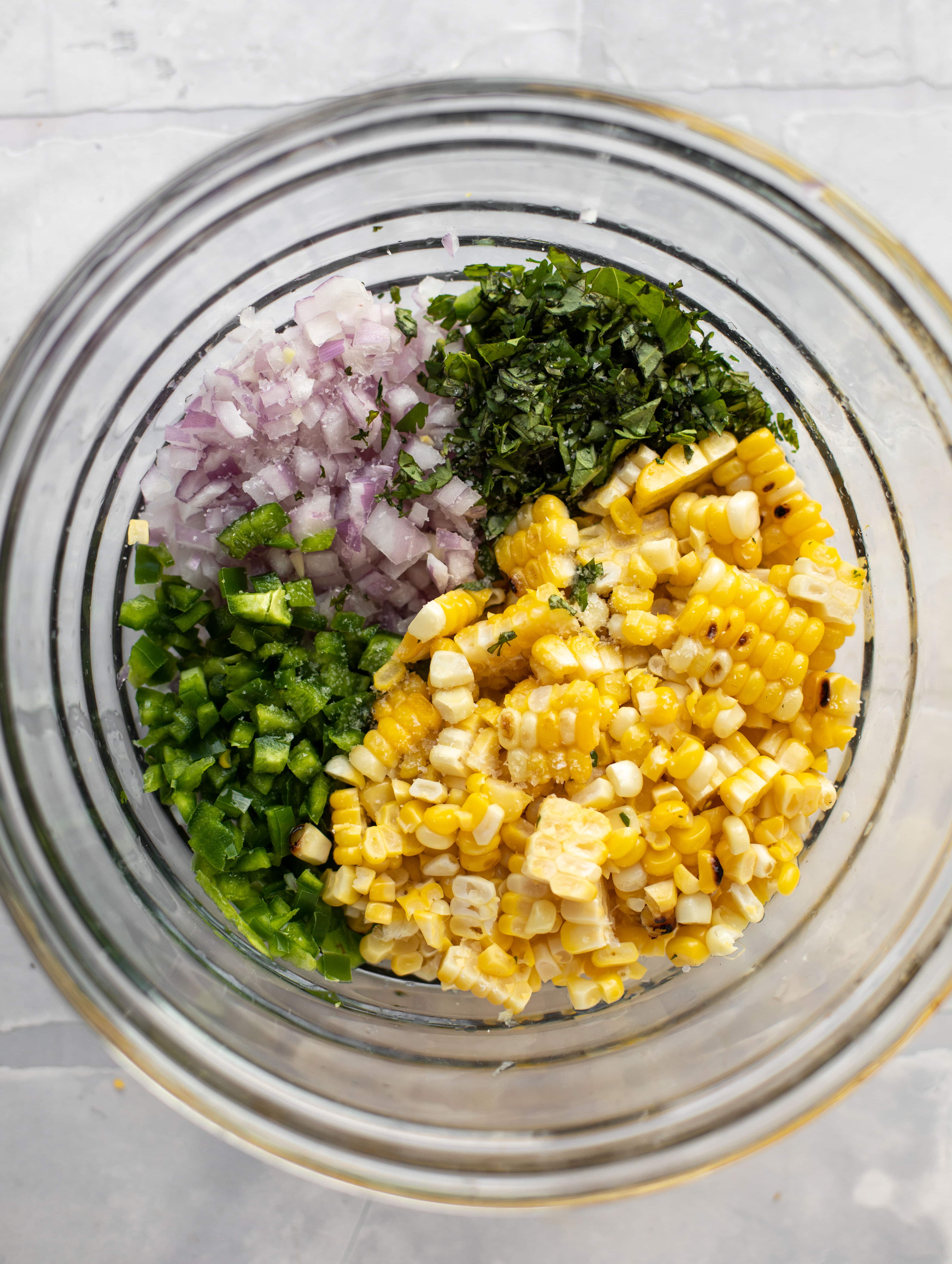 corn, jalapeno, onion, cilantro and basil in a bowl