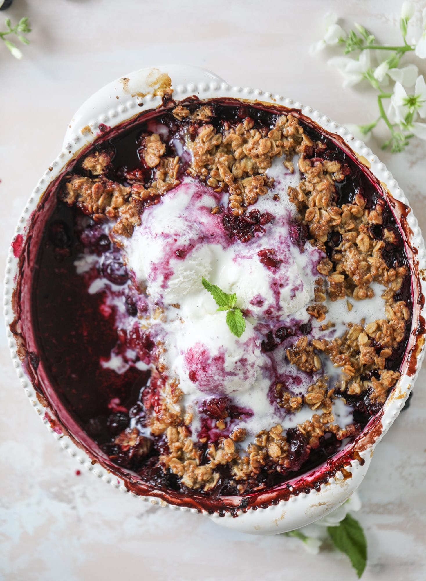 This blueberry crisp is warm and bursting with sweet and juicy fruit. It's topped with a quinoa oatmeal brown sugar topping and is the perfect dessert for summer. Served warm and topped with vanilla ice cream, it's just divine! I howsweeteats.com #blueberry #crisp #quinoa #oats #dessert #fruit 