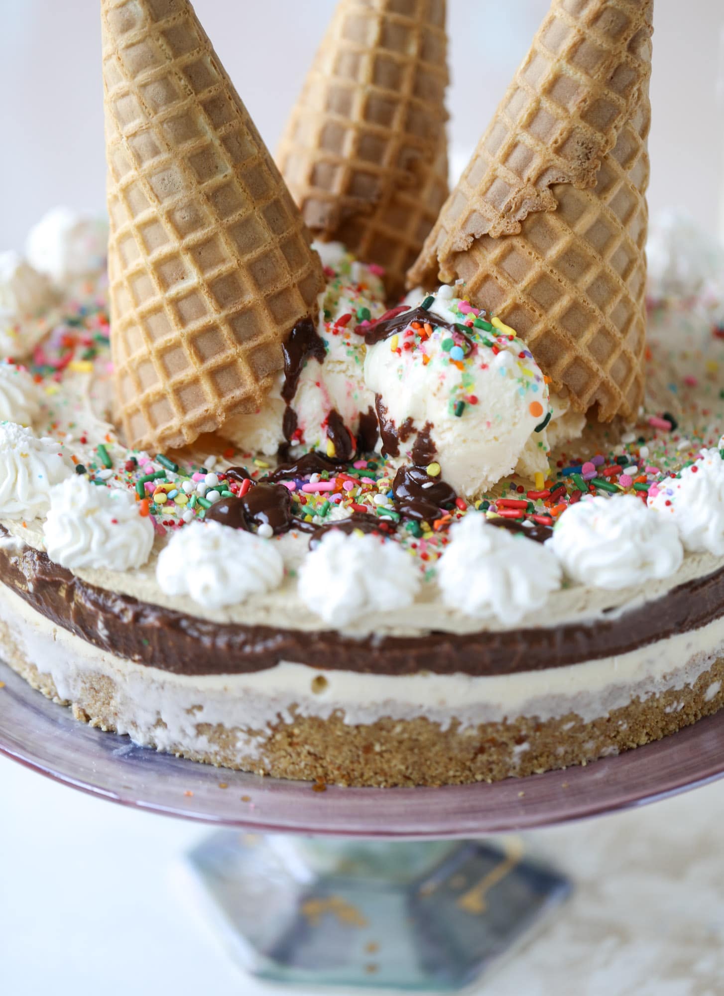This peanut butter fudge ice cream cake is absolutely insane and perfect for summer! A sweet and savory pretzel crust, vanilla ice cream, homemade hot fudge and a peanut butter whipped cream layer take it to the next LEVEL. Delicious! I howsweeteats.com #icecream #cake #peanutbutter #chocolate #pretzel