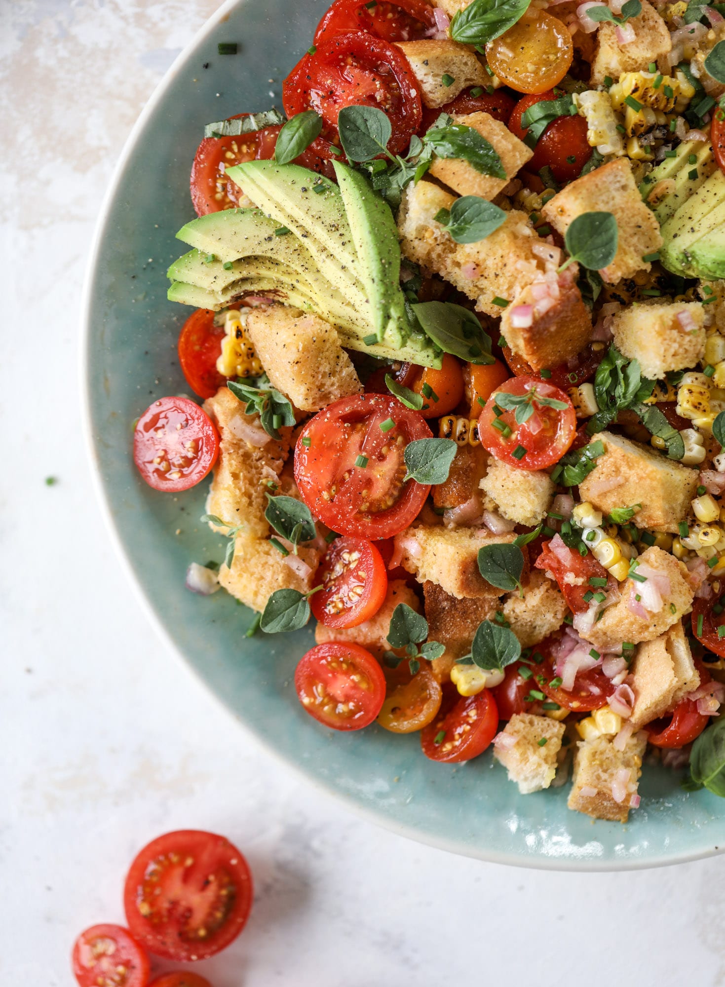 This is the perfect tomato panzanella salad! It's full of juicy, bursting, sweet tomatoes, toasted sourdough bread cubes, fresh herbs, grilled corn, sliced avocado and an incredible homemade dressing that blankets everything in deliciousness. SO good. I howsweeteats.com #panzanella #salad #tomato #basil #summer #corn #avocado #healthy #recipes