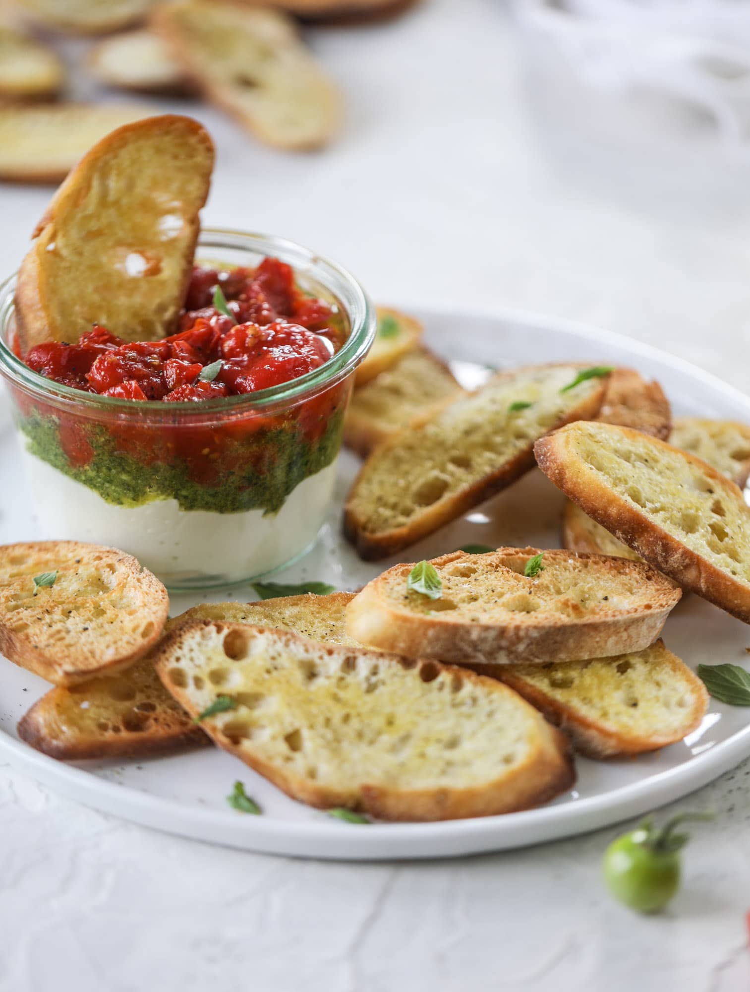 This ricotta jam jar is the perfect appetizer and snack to serve at a party! Based on the ricotta jam jar served at Nordstrom Cafe, it starts with creamy ricotta, is topped with flavorful basil pesto and a quick tomato jam. Serve with crunchy bread and dip dip dip! I howsweeteats.com #ricotta #jam #jar #nordstrom #tomato #pesto #appetizer #dip