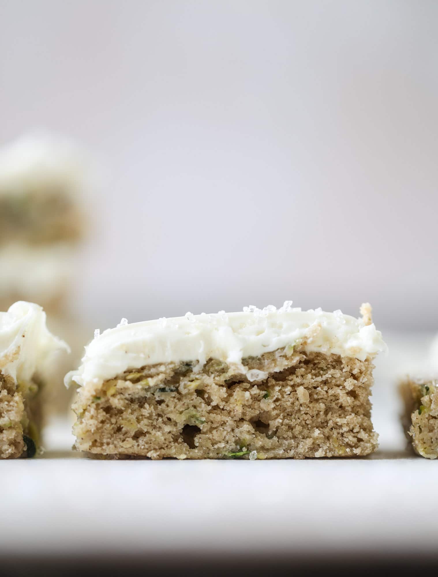 These zucchini bars with cream cheese icing are a fun twist on zucchini bread! Zucchini bars are super easy to make, have a little spice and a lot of flavor, topped with the creamiest cream cheese frosting. Delicious and simple! I howsweeteats.com #zucchini #bars #cream #cheese #icing #dessert