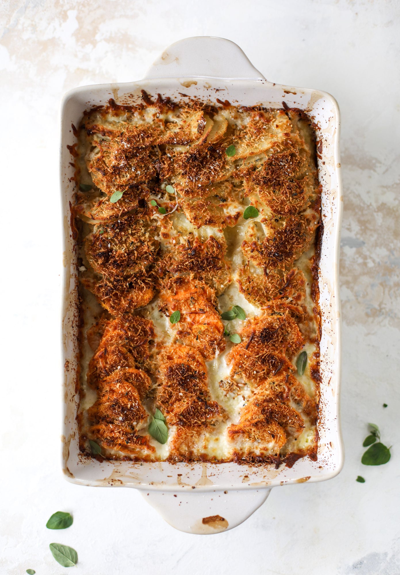 These scalloped potatoes are a cheese lover's dream. Sharp asiago and cream envelops idaho and sweet potatoes in these scalloped potatoes to please everyone! The crunchy asiago topping is irresistible. I howsweeteats.com #scalloped #potatoes