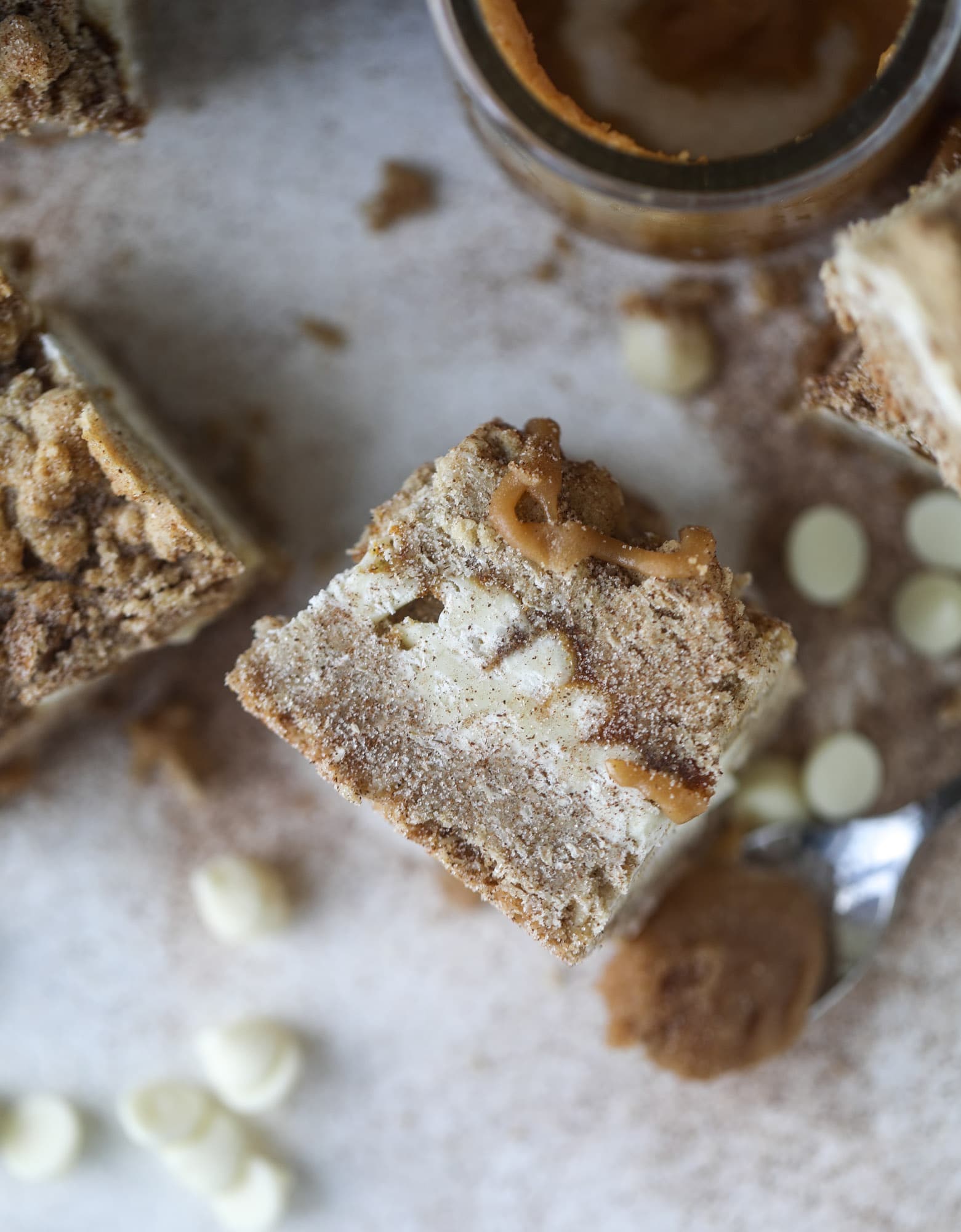 These snickerdoodle caramelitas have a layer of chewy, cinnamon sugared oatmeal bar topped with cream white chocolate and more crumbly, chewy oatmeal bites. They are super delicious and festive! I howsweeteats.com #snickerdoodle #caramelitas