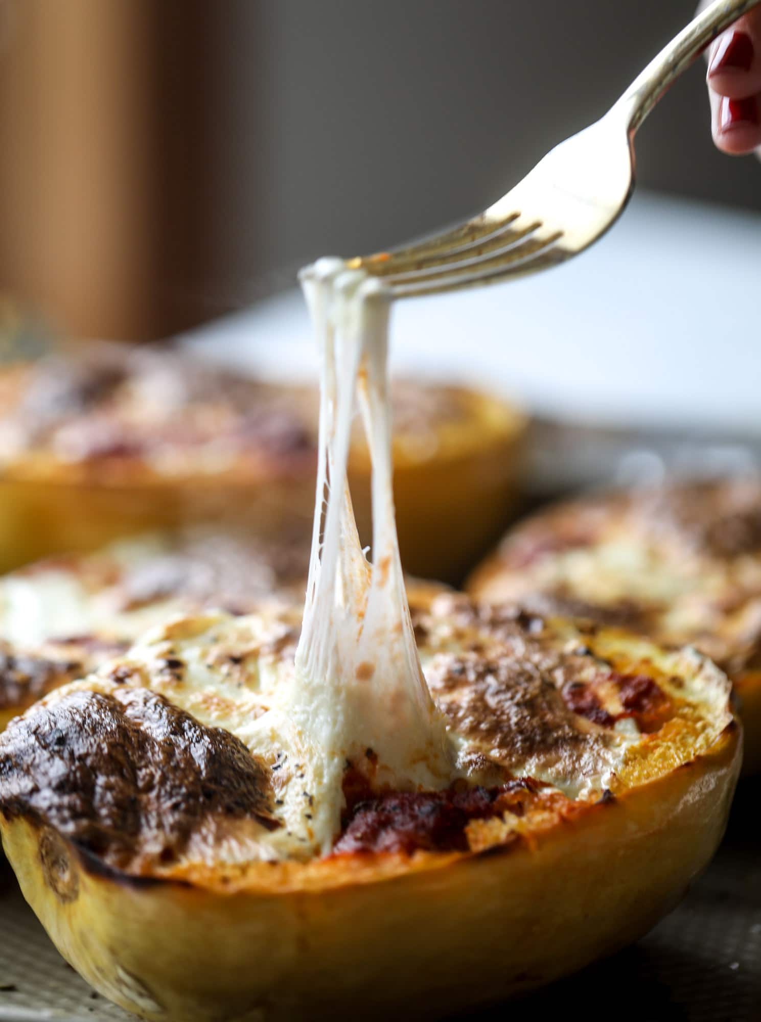Spaghetti squash parmesan is a delicious weeknight meal! Topped with marinara or bolognese, melty cheese and fresh herbs, it's easy and delicious! I howsweeteats.com #spaghettisquash #parmesan