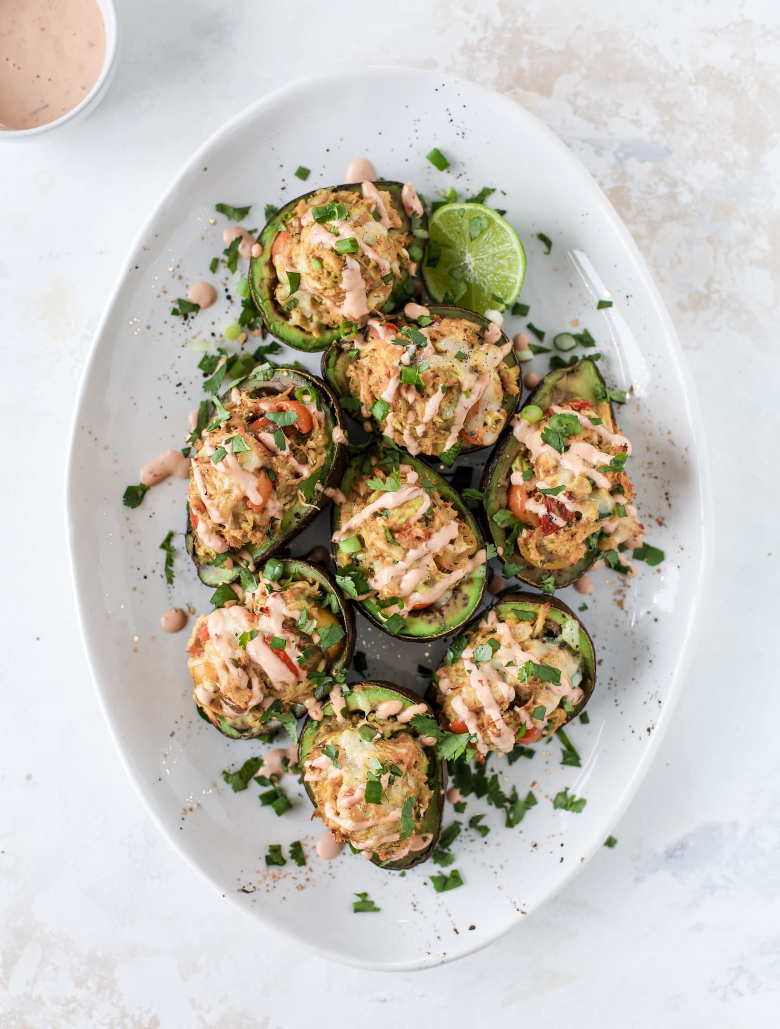 These baked avocados are stuffed with a cheesy chicken mixture and drizzled with sriracha yogurt sauce! Super delicious and an easy weeknight meal. I howsweeteats.com #baked #avocados