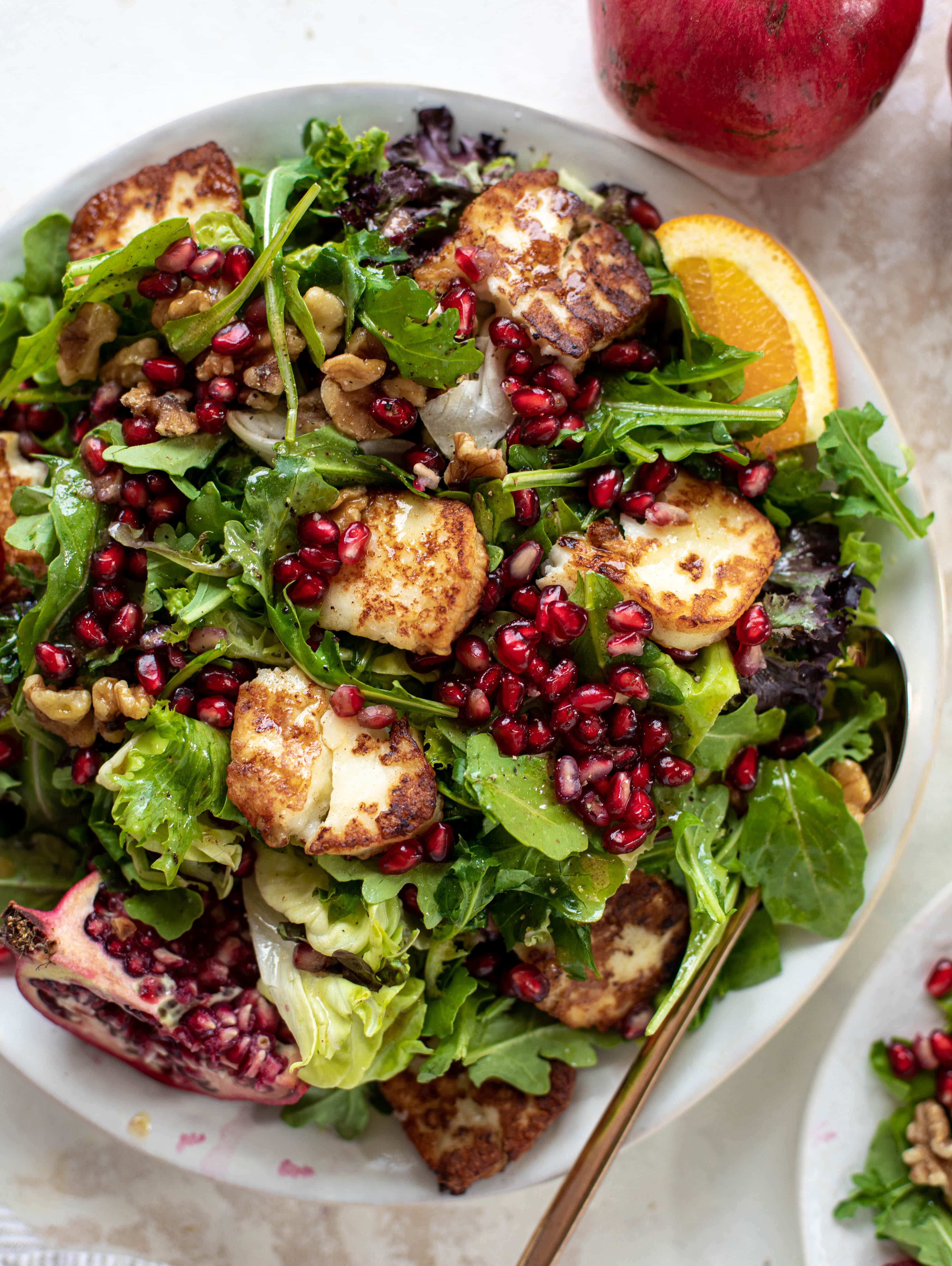 A pomegranate halloumi salad that's the perfect starter to your holiday meal! Drizzle with a spiced orange vinaigrette for the most festive flavor ever.