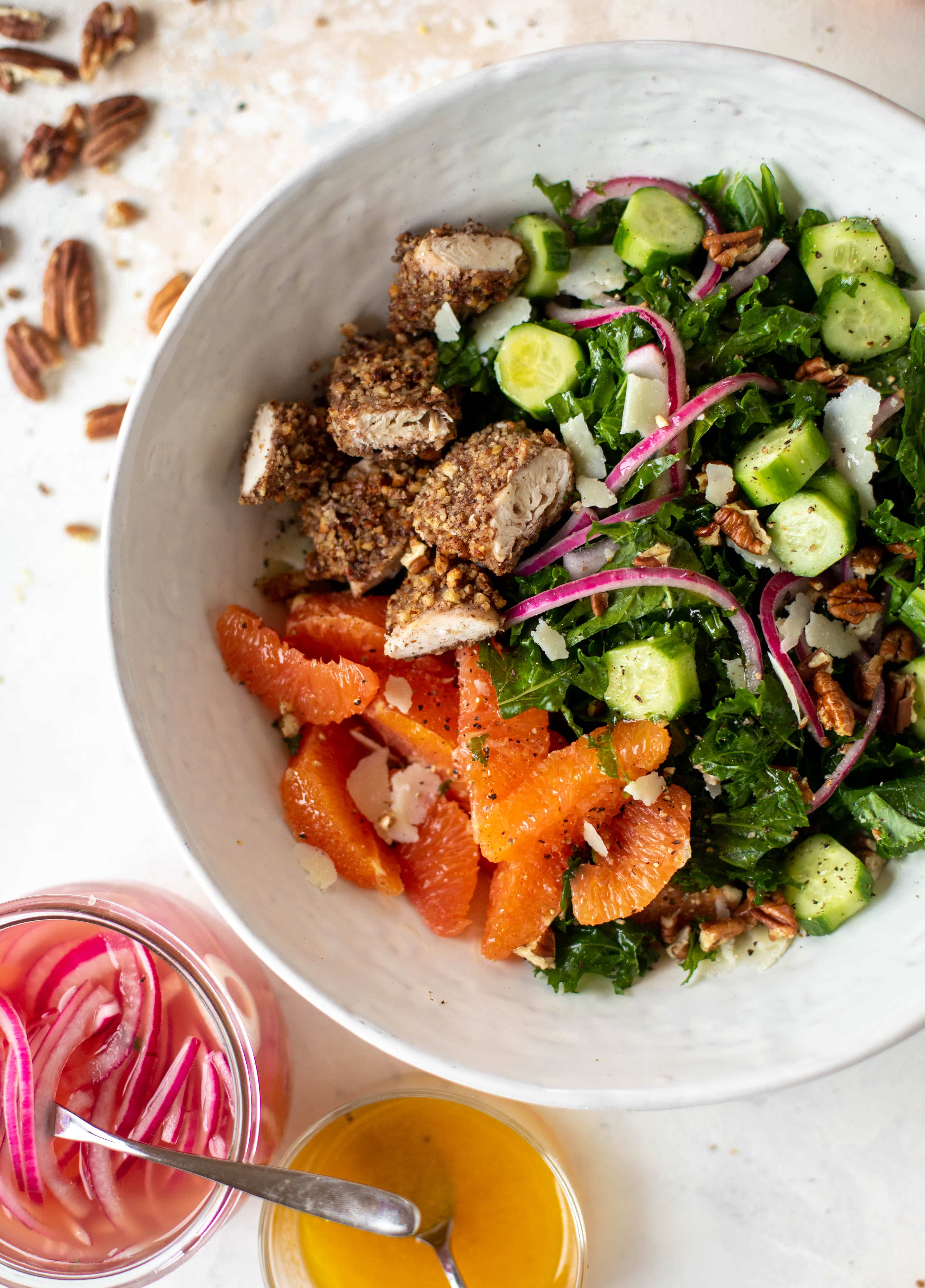 This pecan crusted chicken salad is so hearty! Kale, cara cara oranges, pickled onions, cucumbers and pecorino make this a bowl of flavor.