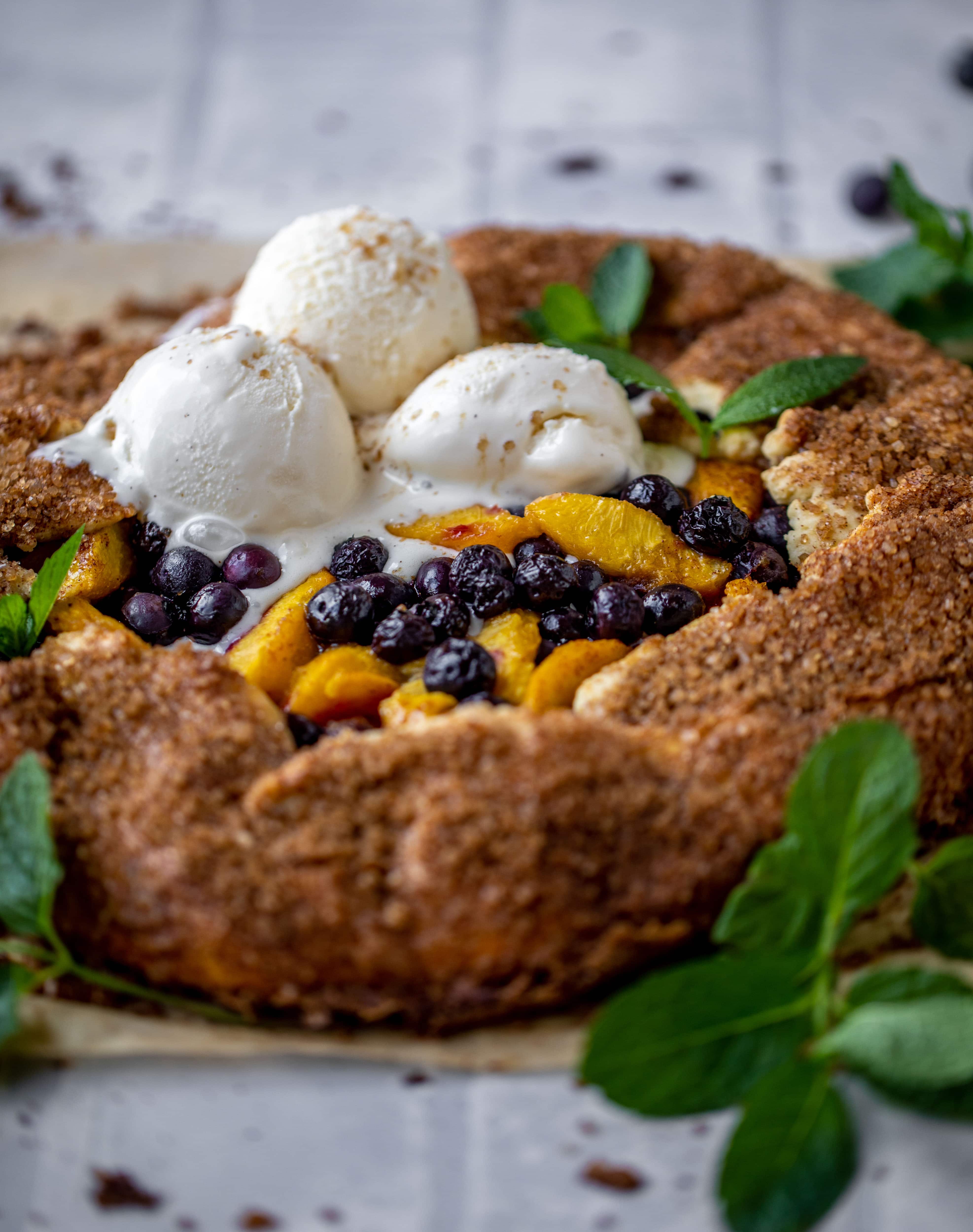 blueberry peach galette with cinnamon sugar galette topped with ice cream and fresh mint