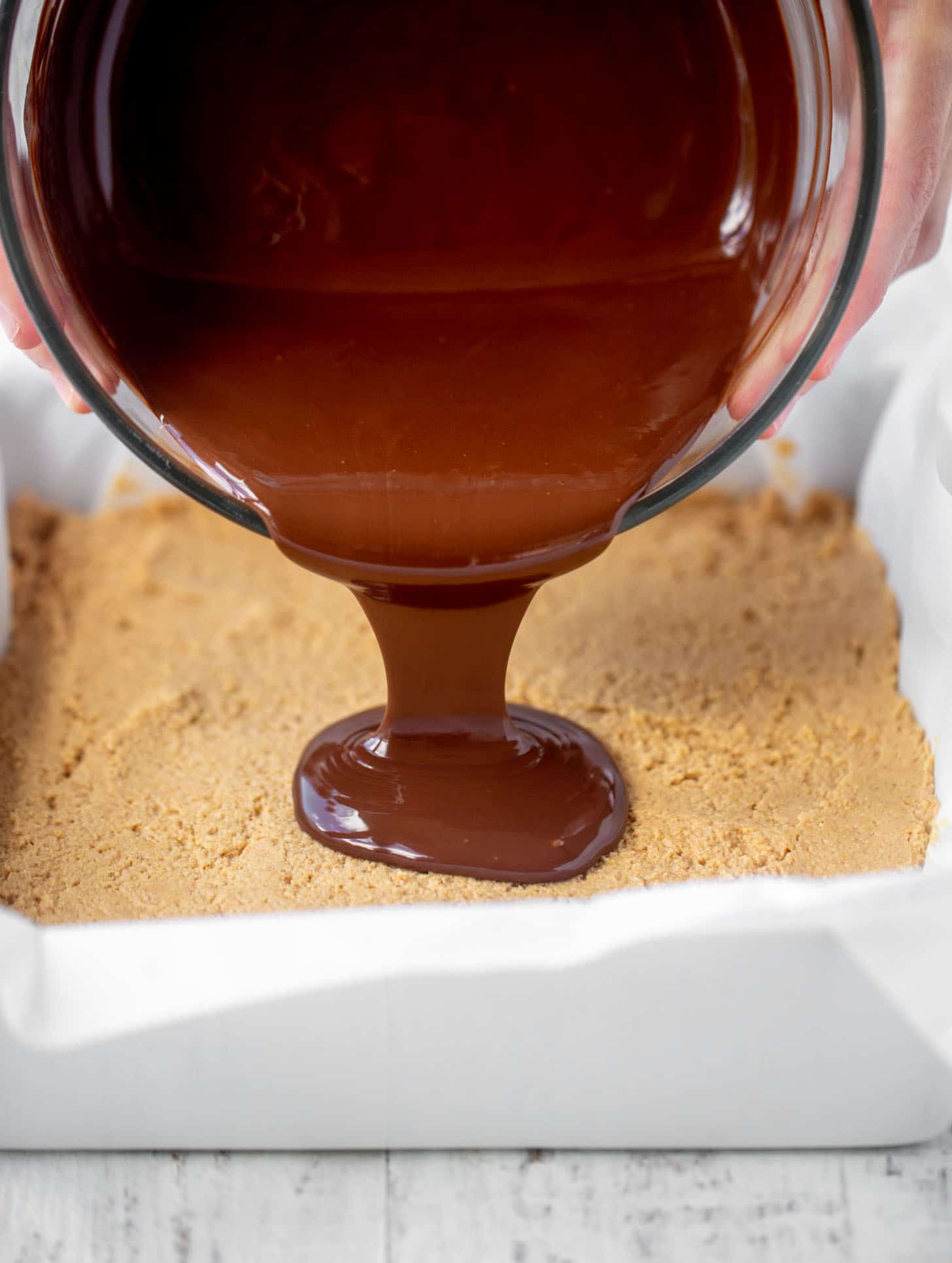 pouring chocolate on peanut butter bars
