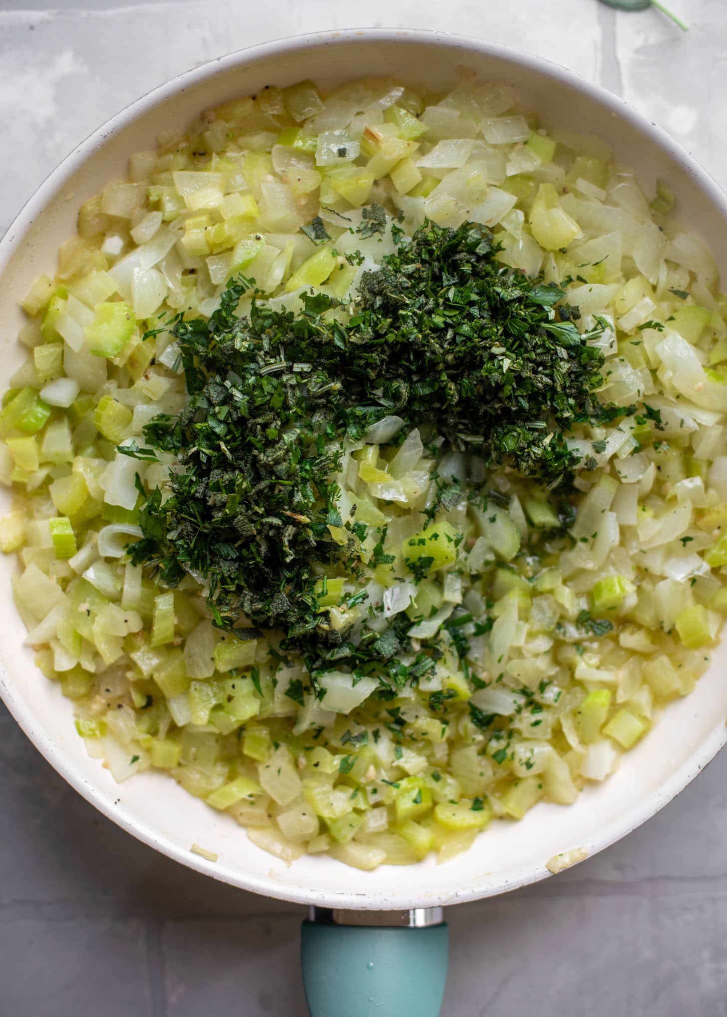 fresh herbs with celery, onion and butter in the skillet