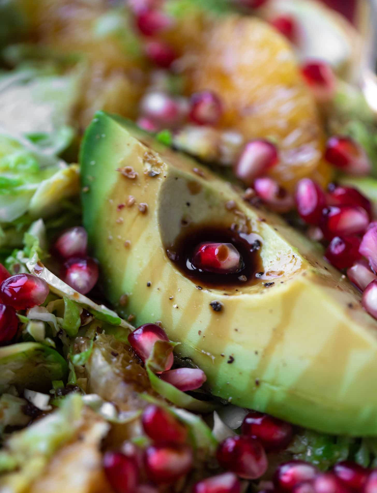 shredded citrus brussels sprouts salad with avocado and pomegranate