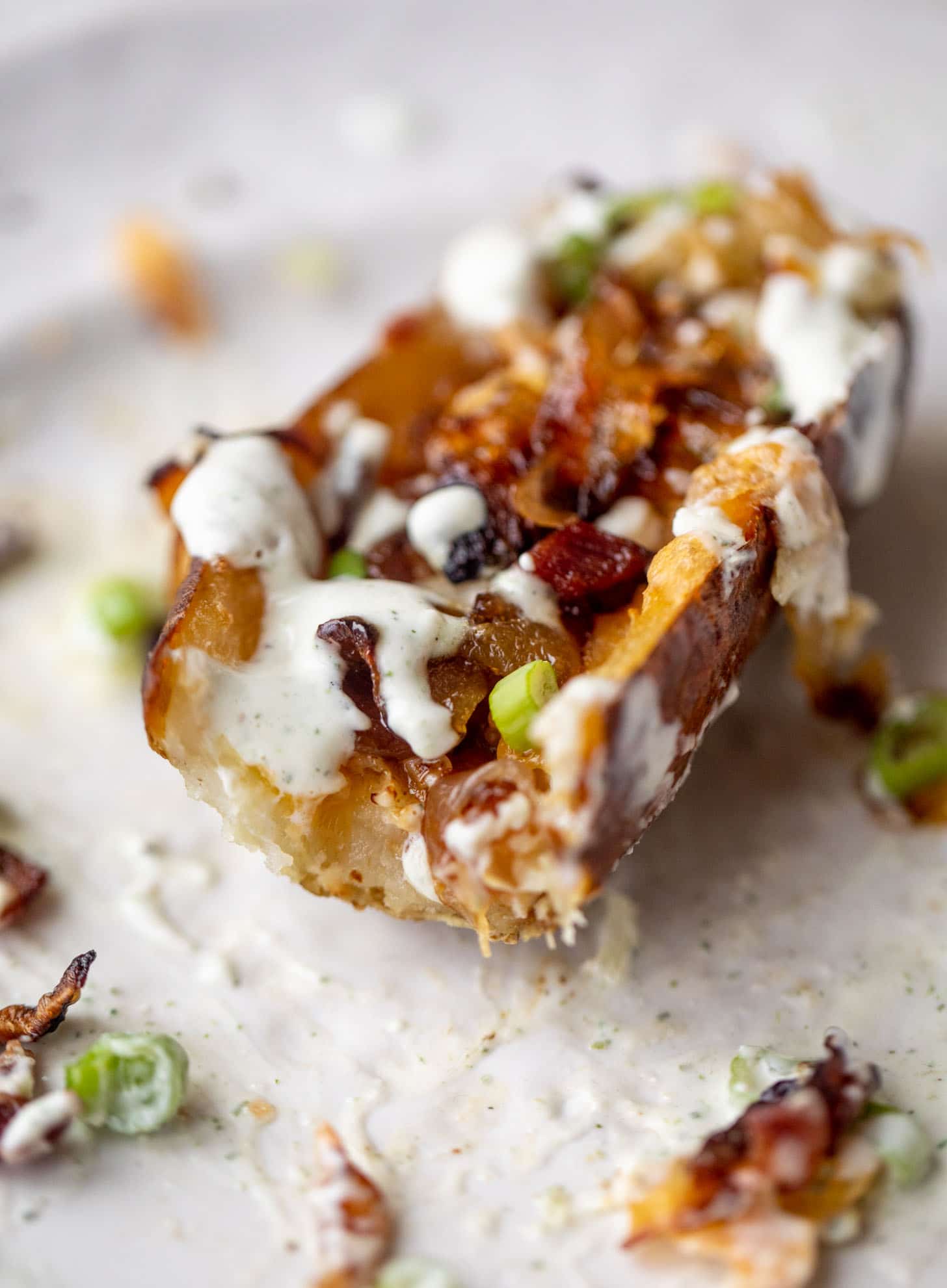 bite out of smoked cheddar and caramelized onion potato skins with ranch