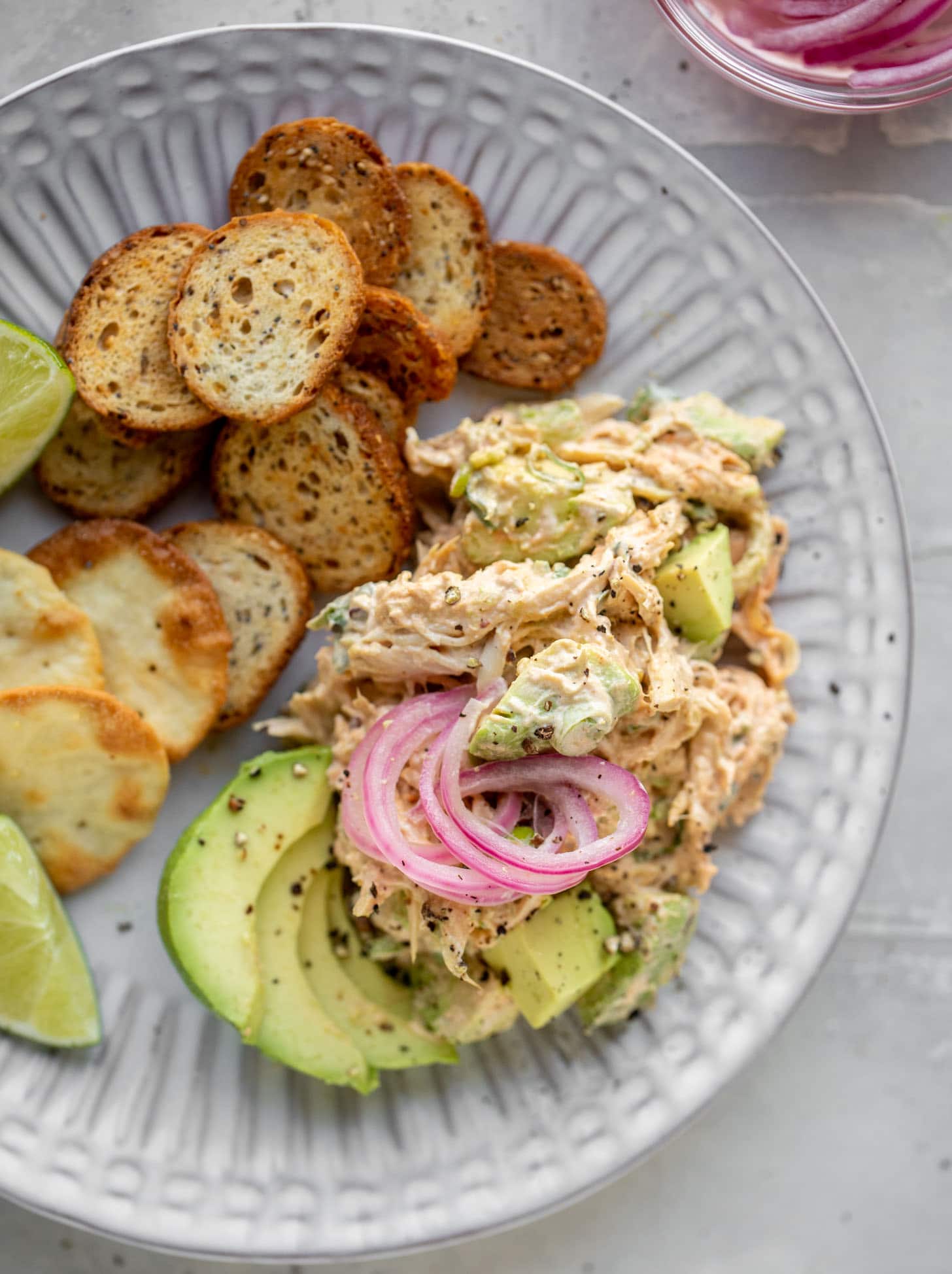 avocado chicken salad with crackers and pickled onions