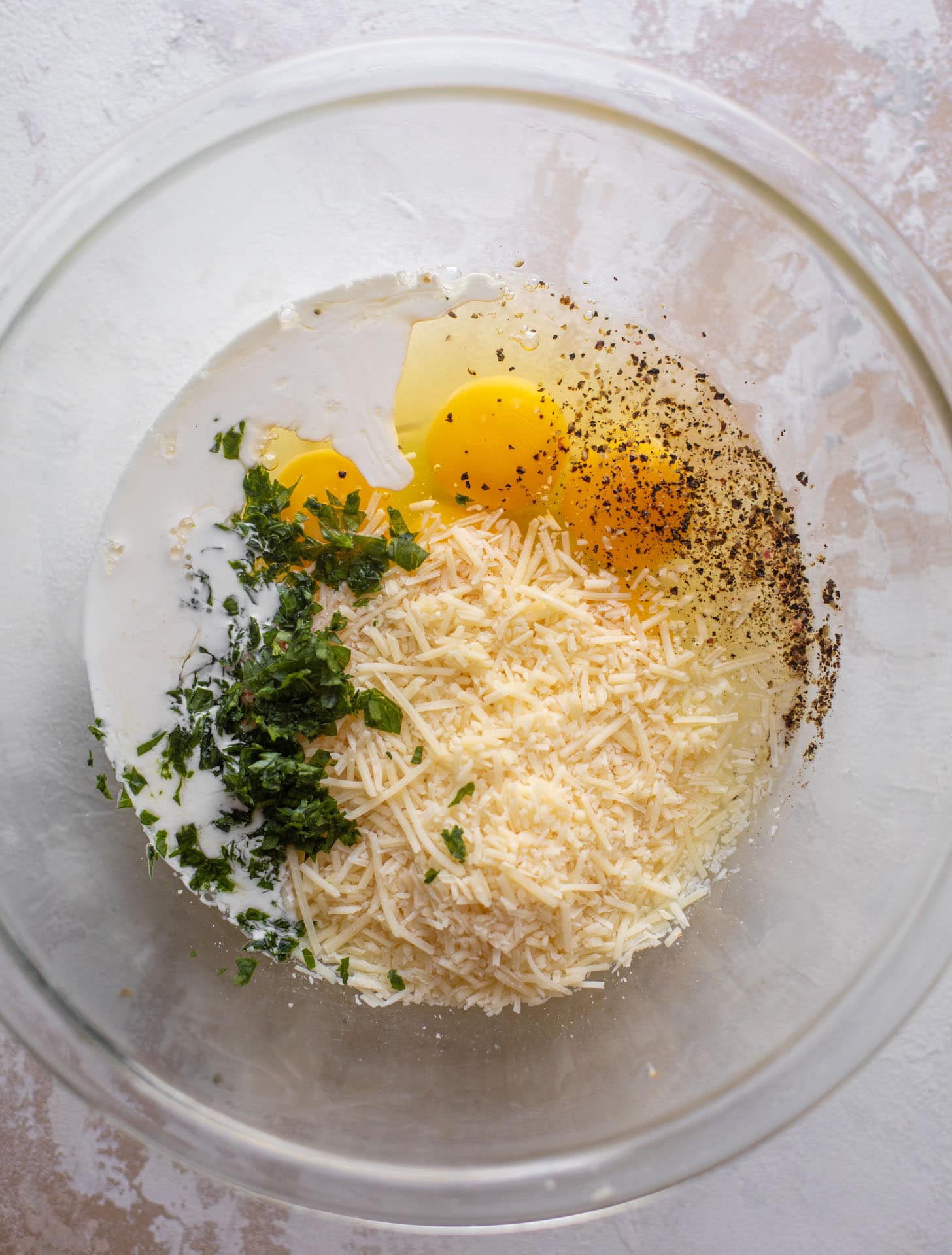 eggs, parmesan, herbs, cream in a bowl