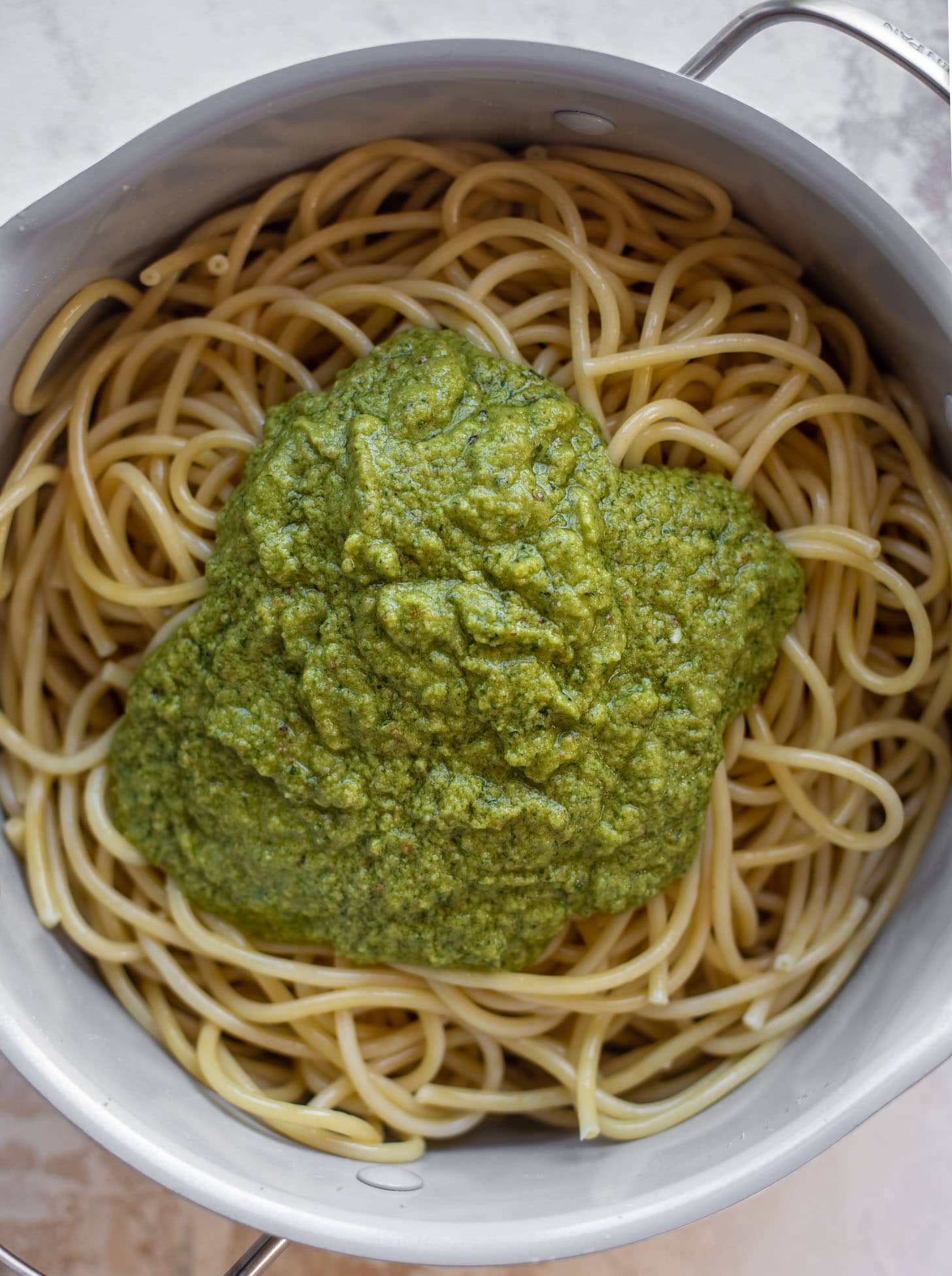 bucatini topped with pesto in a pot