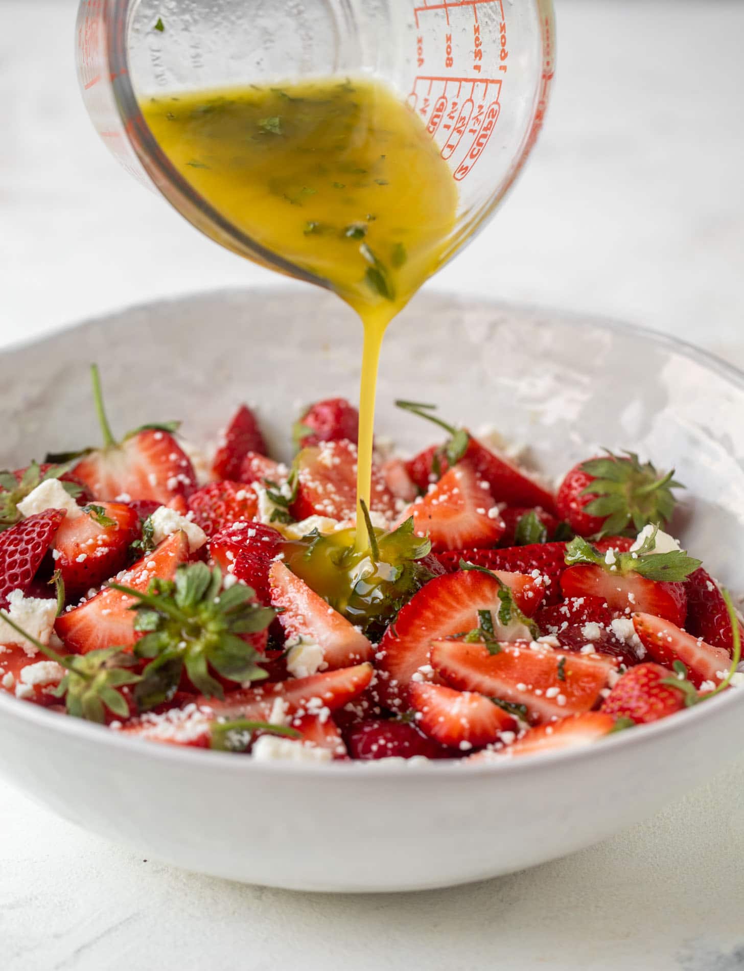 pouring champagne dressing on strawberry salad